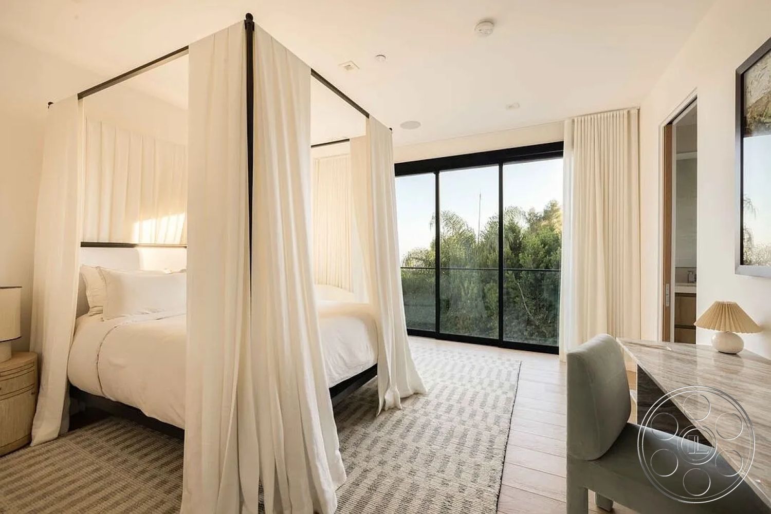 Modern 512 - neutral color palette, natural light-filled space, contemporary design style, clean lines and open layout, interior bedroom with canopy bed, textured white fabric drapery, light hardwood bedroom floors, modern glass balcony doors, minimalist desk with marble top, woven area rug in neutral tones, understated bedside lamp, large windows with outdoor view, simple decorative accents