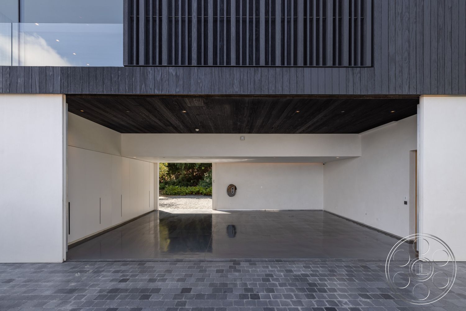 Modern 513 - white stucco walls, landscaped garden view, modern architectural style, natural light from large windows, minimalist design details, clean lines and geometric forms, contemporary home design, exterior garage entrance, polished concrete garage floor, exposed black wood ceiling, cedar wood slatted facade, gray stone driveway pavers, open space interior layout