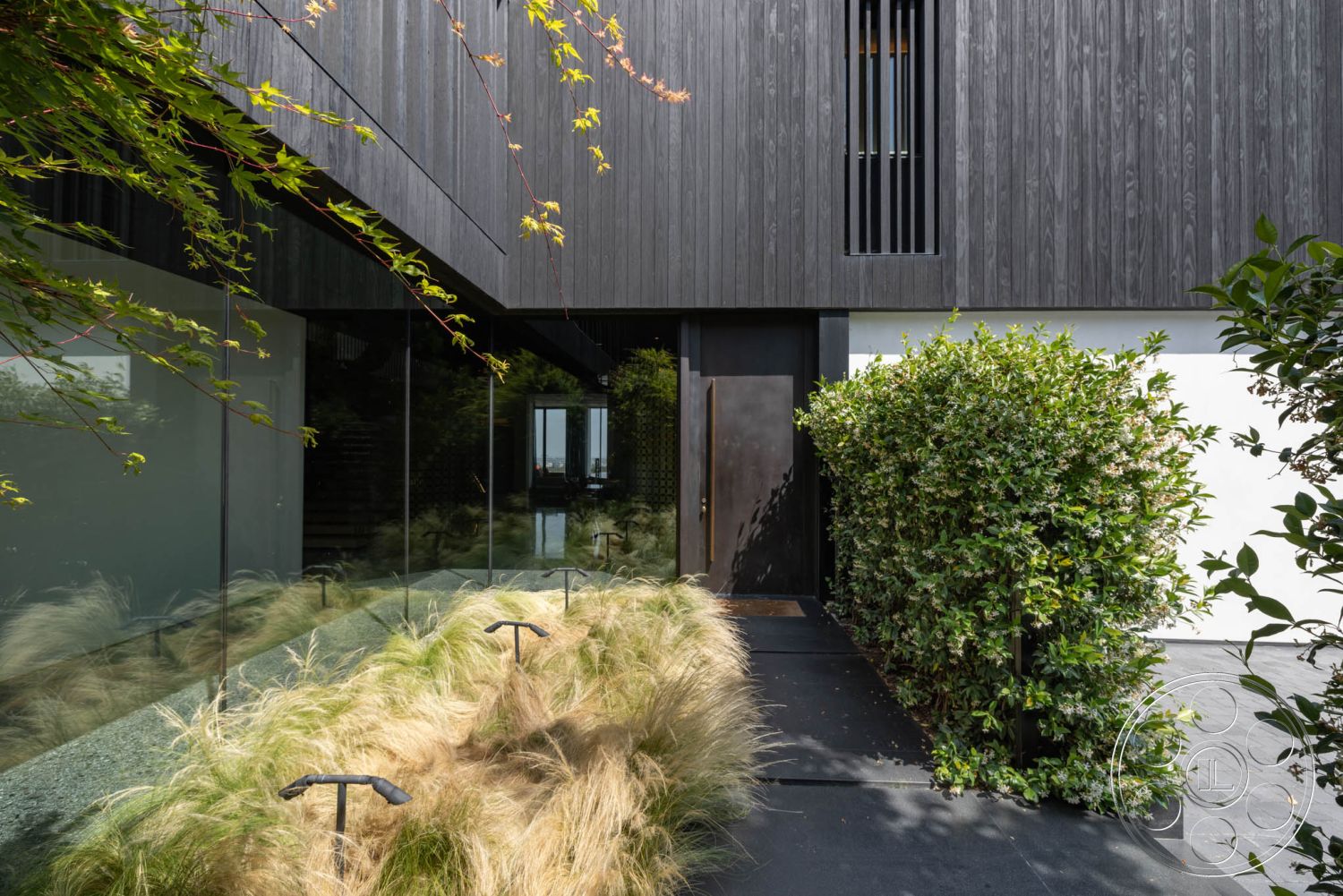 Modern 513 - exterior, surrounding greenery, suburban setting, slate stone pathway, natural light-filled space, textured wood finish, minimalist architectural style, structured landscaping, modern home entrance, landscaped garden with ornamental grasses, wood paneling facade, glass wall entryway, black metal door, pruned hedge borders, contemporary exterior details, open air aesthetic