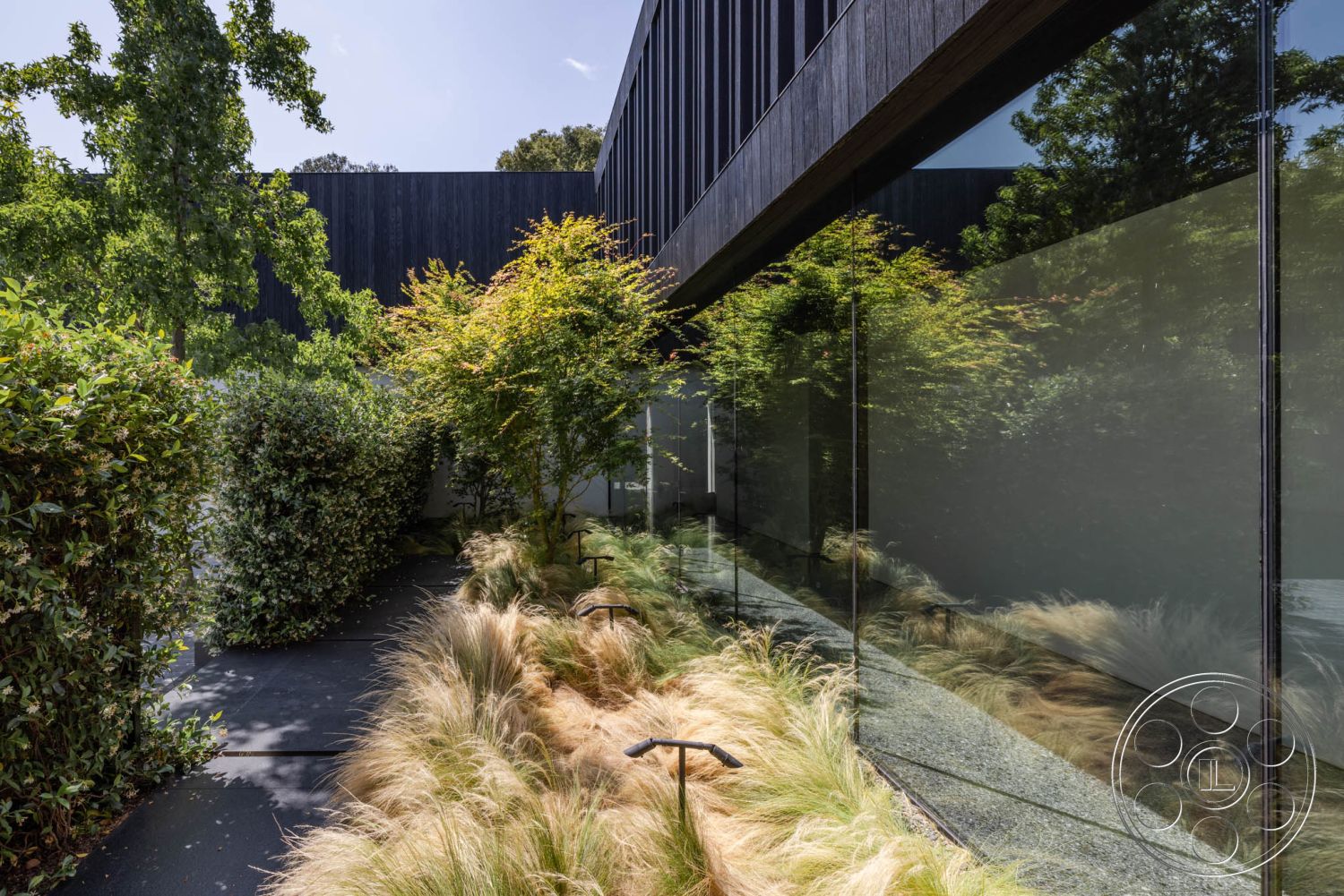 Modern 513 - low-maintenance landscaping, minimalist design elements, exposed aggregate concrete, modern architectural design, framed glass panels, exterior glass curtain wall, exterior concrete pathway, urban setting with greenery, contemporary garden setting, exterior wooden siding, landscape greenery accents, landscape ornamental grasses, black wooden wall cladding, textured outdoor surfaces, natural light reflection on glass, sustainable outdoor design, integrated natural elements, clear sightlines to the outdoor space, strategically placed shrubs, dense plant borders