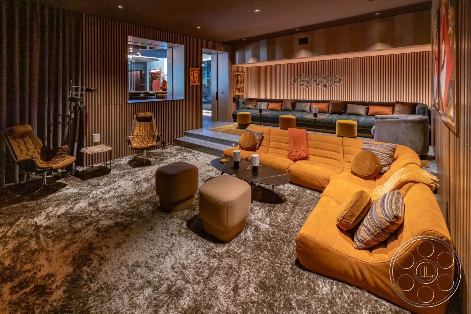 Modern 513 - neutral color palette, open floor plan, light wood finishes, glass coffee table, modern art wall decor, sliding glass doors, contemporary design elements, textured plaster walls, decorative throw pillows, multiple seating areas, dim ambient lighting, recessed lighting fixtures, modern lounge seating, wood panel accent wall, exposed wood ceiling details, orange velvet sectional sofa, shaggy area rug, home theater area, high-end entertainment setup, stylish curtain treatments