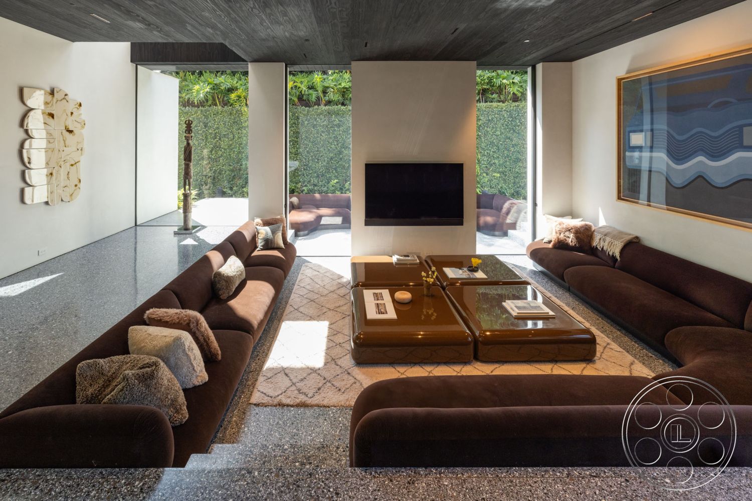 Modern 513 - polished concrete floor, open floor plan, large floor-to-ceiling windows, contemporary art piece, interior living room, natural light-filled space, modern sectional sofa, minimalist design style, exposed wood ceiling, slate accent wall, brown velvet upholstery, square glass coffee table, geometric patterned area rug, neutral toned wall art, green hedge view, comfortable lounging area