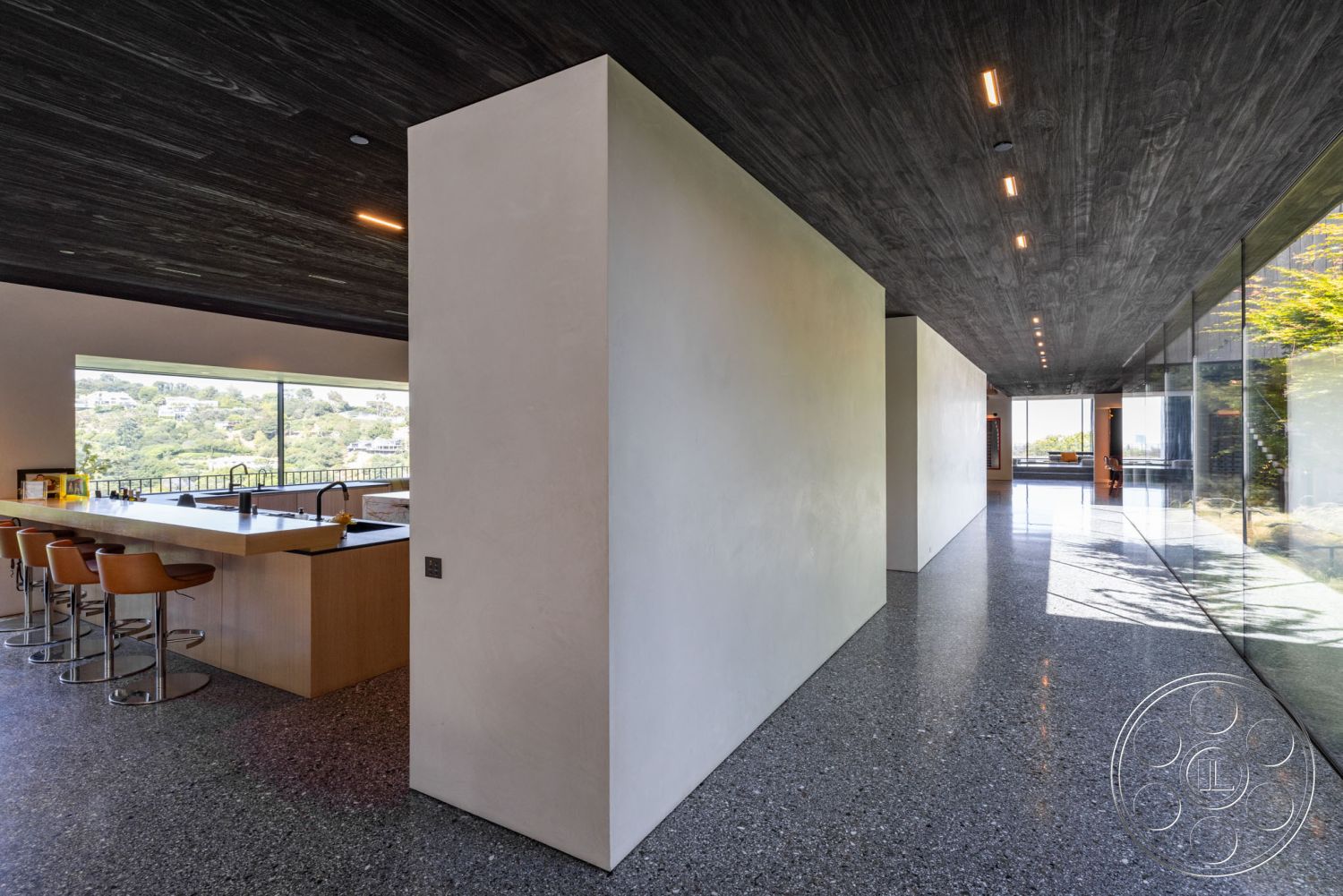 Modern 513 - polished concrete flooring, modern pendant lighting, sleek cabinetry, large floor-to-ceiling windows, granite kitchen countertop, natural light-filled space, wood beam ceiling, integrated kitchen appliances, terrazzo floor finish, minimalist white walls, interior modern architecture, open plan kitchen with bar seating, steel kitchen fixtures, clean lines and contemporary design, view of surrounding hillside, spacious hallway with natural light, elevated home overlooking landscape