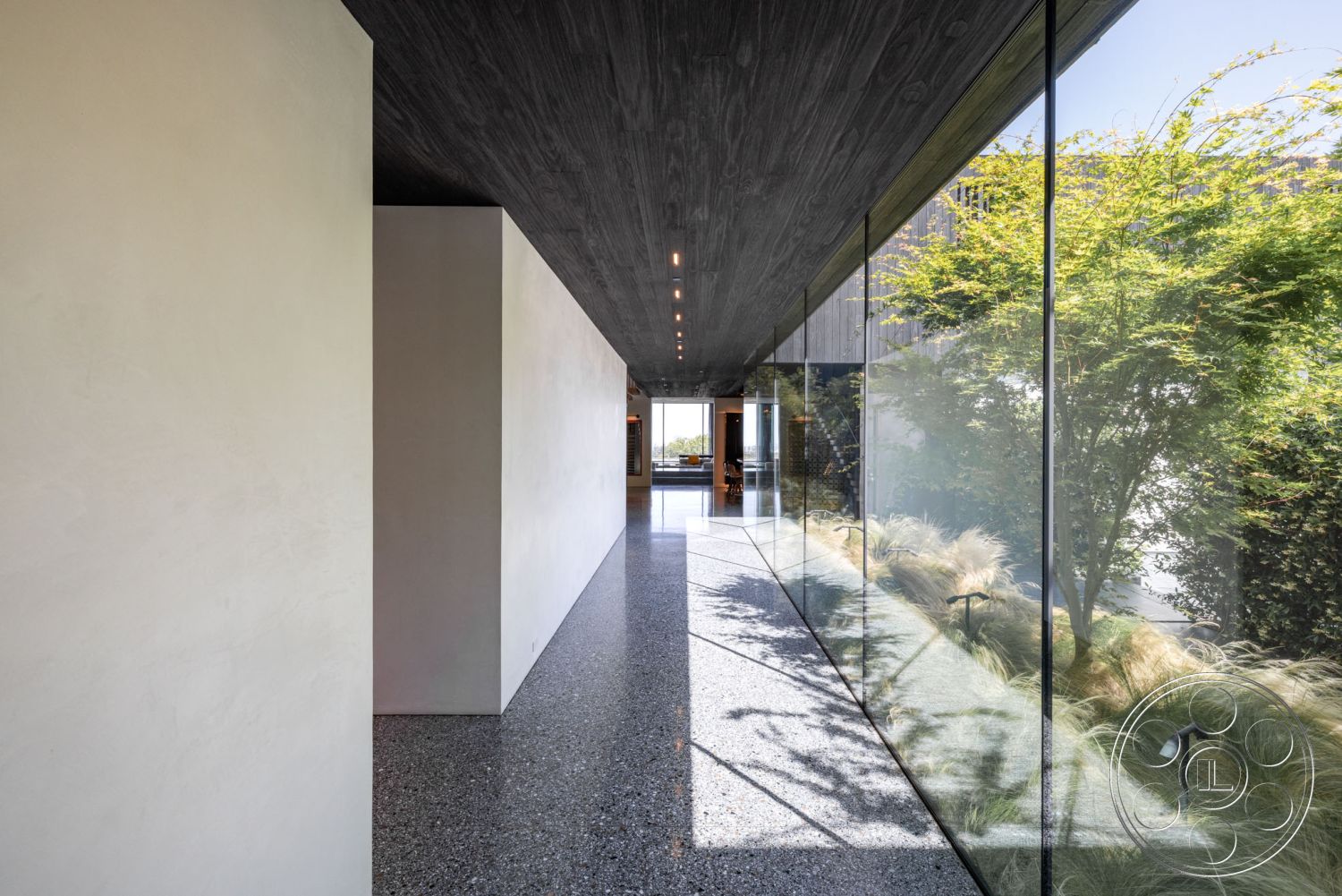 Modern 513 - modern interior, contemporary materials, indoor-outdoor connection, open-concept layout, sustainable design features, textured wall details, minimalist architectural style, floor-to-ceiling glass walls, interior hallway design, smooth plaster walls, landscaped outdoor view, exposed aggregate polished concrete floor, dark wood ceiling panels, natural light corridor