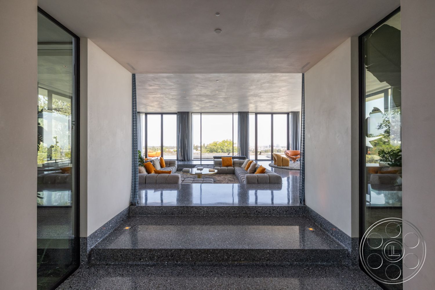 Modern 513 - minimalist decor, neutral color palette, large glass sliding doors, exposed concrete walls, modern coffee table, floor-to-ceiling windows, urban skyline view, textured plaster ceiling, seamless indoor-outdoor flow, soft textile accents, interior recessed lighting, natural light-filled space, open floor plan design, contemporary sectional sofa, interior polished terrazzo flooring, contemporary armchairs, geometric architectural shapes, minimalist modern living room, steel window frames, orange throw pillows