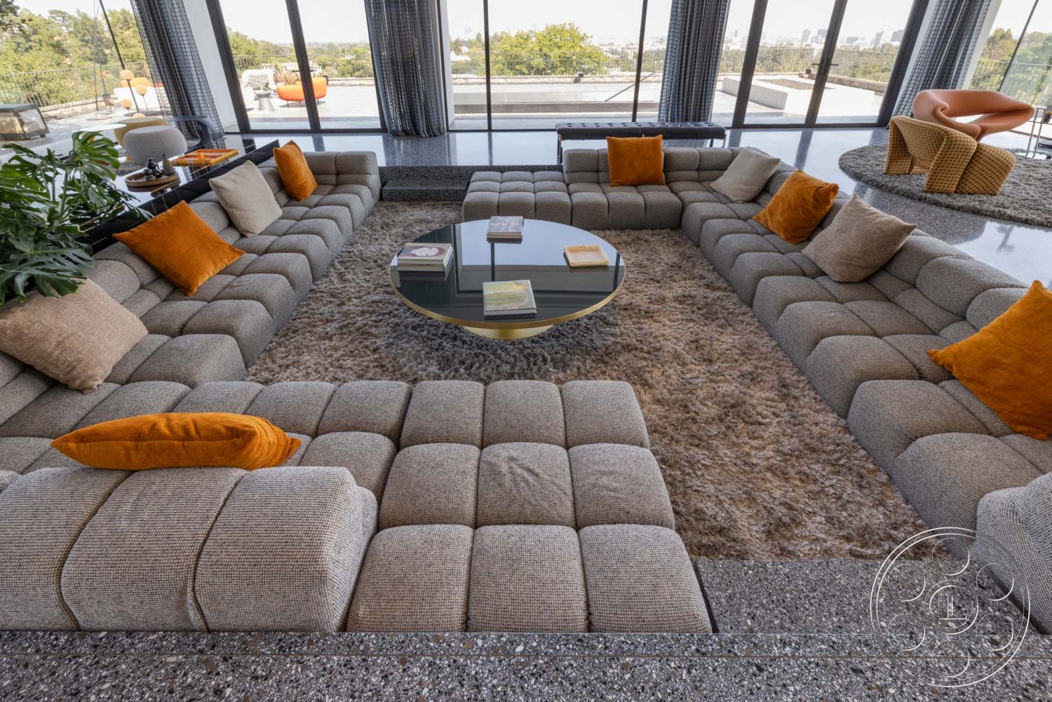 Modern 513 - natural light, minimalist design, concrete flooring, urban view, stylish armchair, open-concept layout, plant decoration, round glass coffee table, interior modern living room, large panoramic windows, textured gray upholstery sectional sofa, plush beige area rug, warm accent pillows