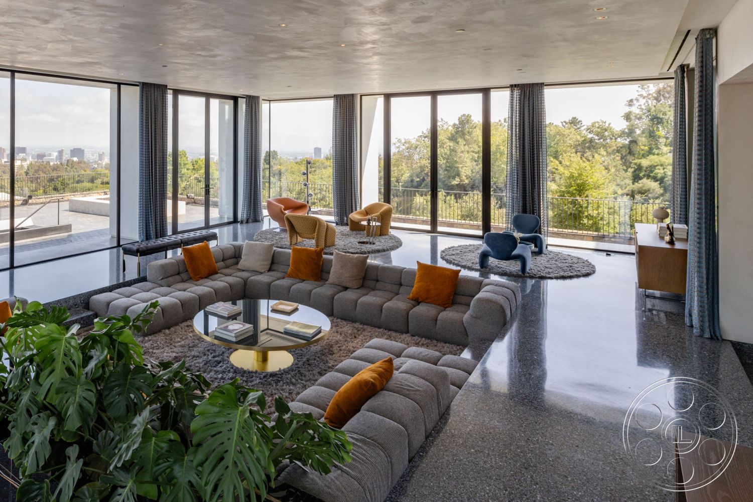 Modern 513 - modern architectural style, open concept living space, large floor-to-ceiling windows, contemporary interior design, textured plaster wall finish, terrazzo flooring living room, glass wall overlooking forest view, modular sectional sofa with accent pillows, round coffee table with gold base, comfortable seating area with armchairs, soft area rug on polished concrete floor, decorative plant accent for greenery, ample natural light from outdoor patio, views of surrounding greenery, luxurious interior space