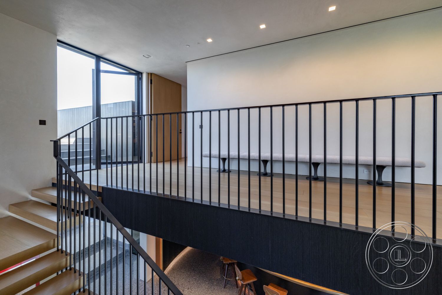 Modern 513 - neutral color palette, contemporary style, minimalist aesthetic, natural wood flooring, urban setting, multi-level design, textured ceiling, open loft space, large floor-to-ceiling windows, modern seating area, light-filled interior, smooth plaster wall finish, black metal stair railings, interior wooden staircase, architectural detail in railing design, wood accent bench