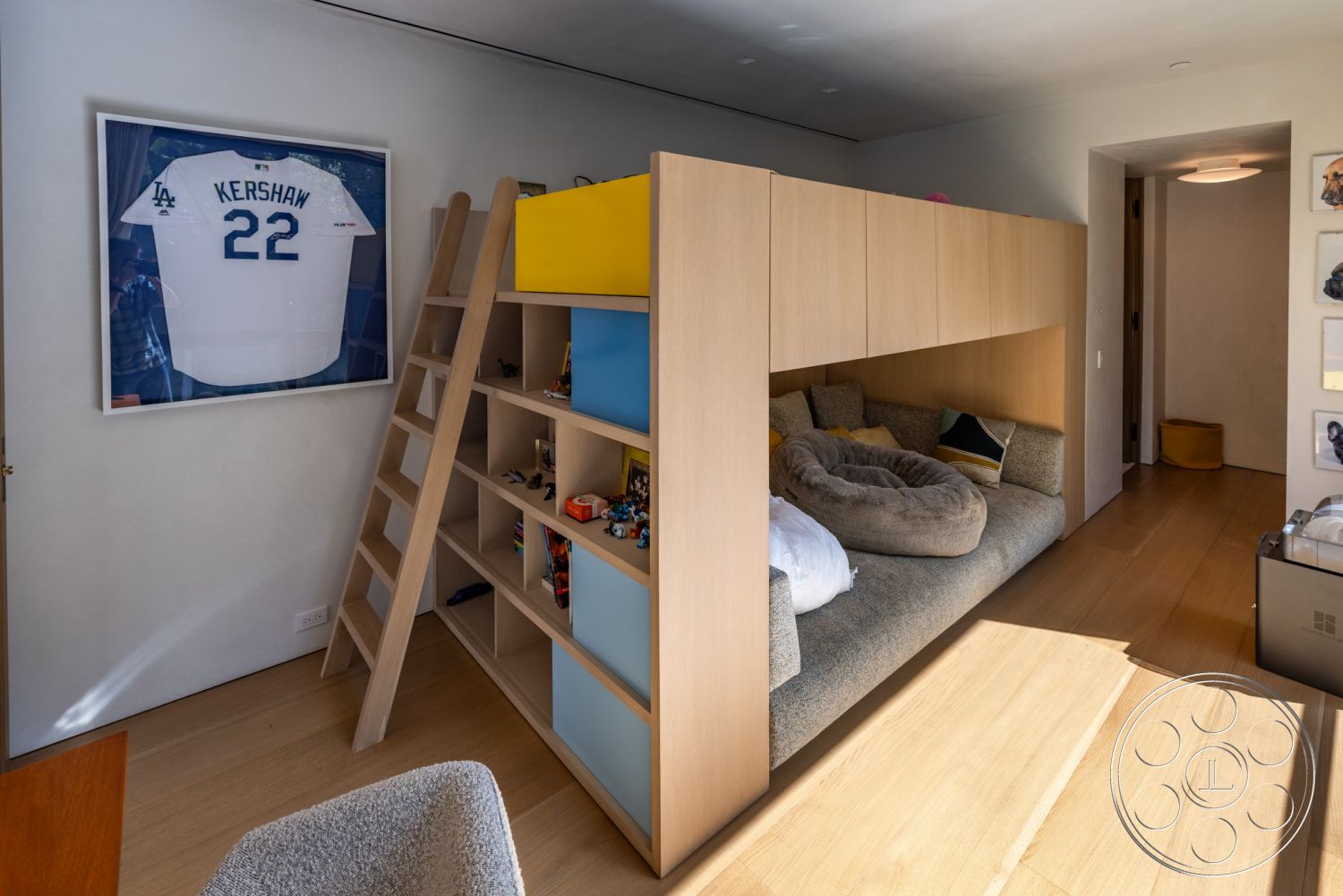 Modern 513 - minimalist aesthetic, soft gray upholstery, stylish accent pillows, cozy reading nook, child's bedroom, contemporary design style, soft textile bedding, compact space utilization, natural wood wall shelving, multicolored modular wood storage units, light-toned hardwood flooring, framed sports memorabilia, custom built-in loft bed, bright, airy room layout, accessible ladder for loft bed