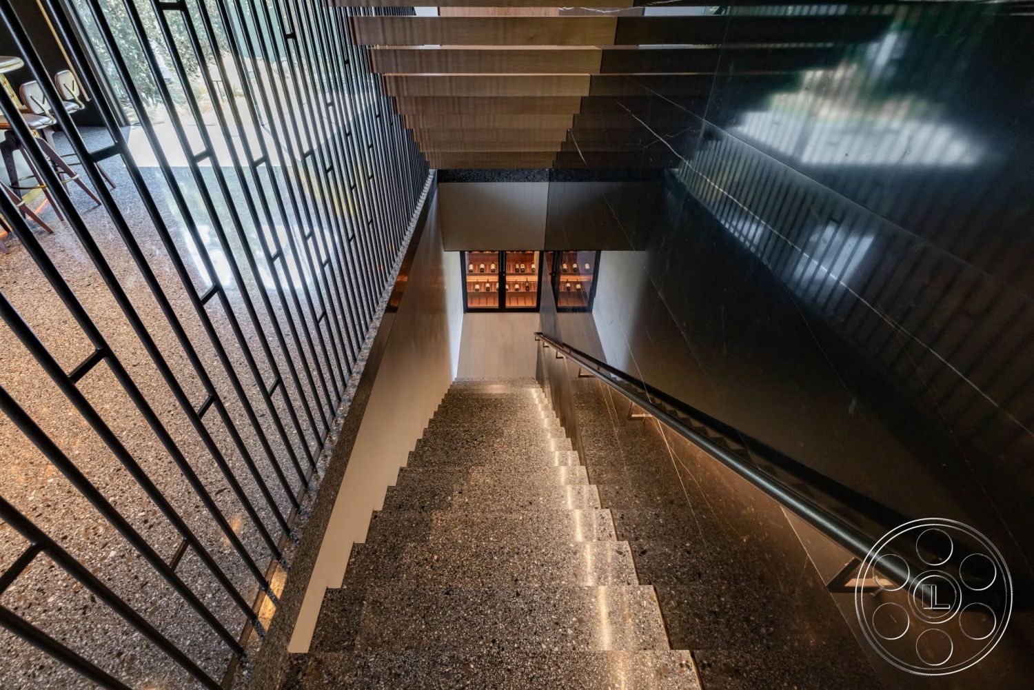 Modern 513 - neutral color palette, modern architectural style, interior spiral staircase, polished concrete stair tread, black glass wall panels, steel stair railings with geometric design, gaussian curve staircase, terrazzo flooring at base of stairs, minimalist lighting under stairs, open space with natural light, exposed concrete wall at stair landing, transom windows above stairwell, built-in storage shelves adjacent to stairs, textured metal railing, architectural detail with clean lines