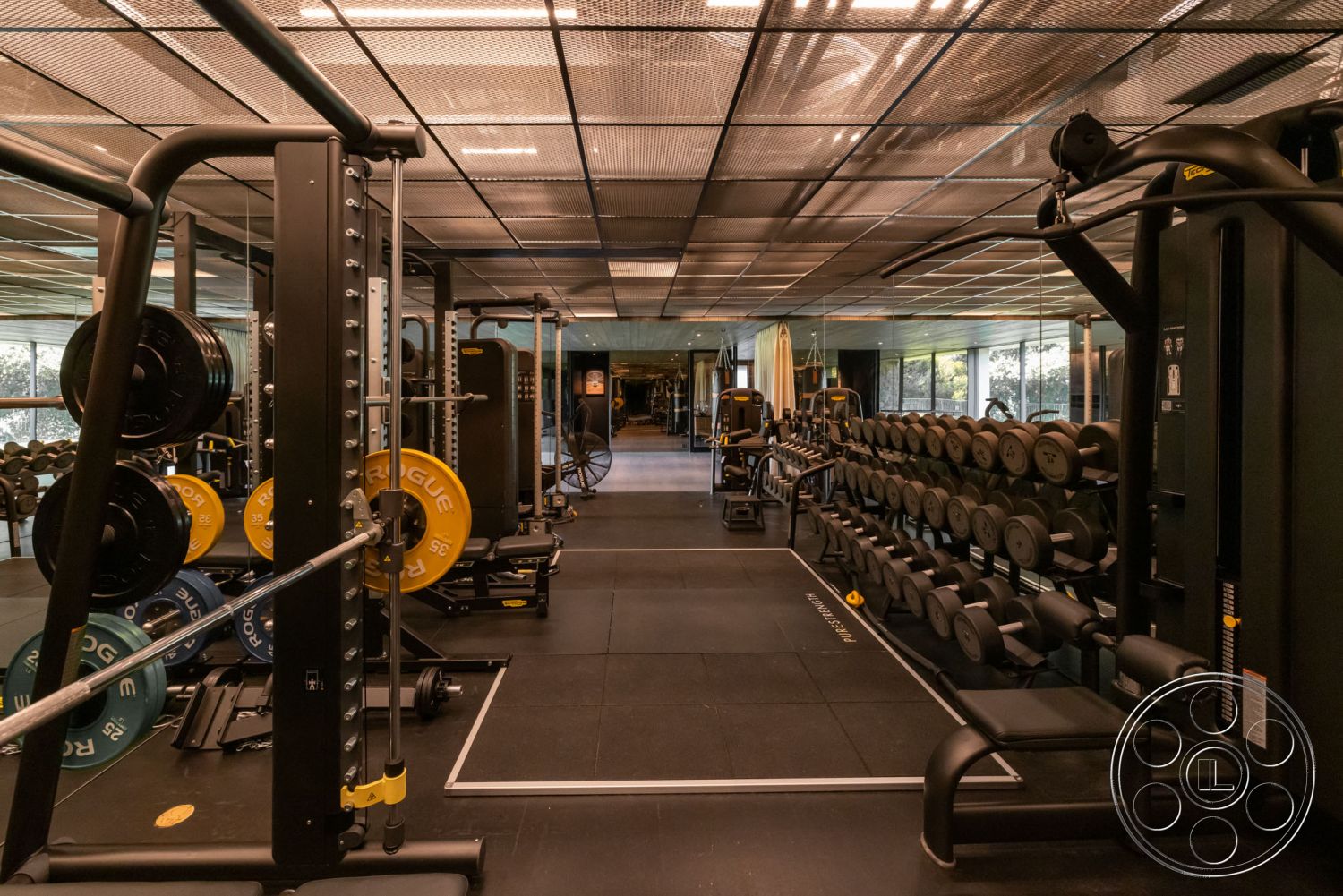 Modern 513 - interior fitness room, functional training space, rubber flooring gym area, metal weight racks, black wall mirrors, glossy ceiling tiles, free weights storage, commercial gym equipment, glass windows with outdoor view, weightlifting platform, steel cable machines, open layout gym design, ambient lighting gym, modern exercise area