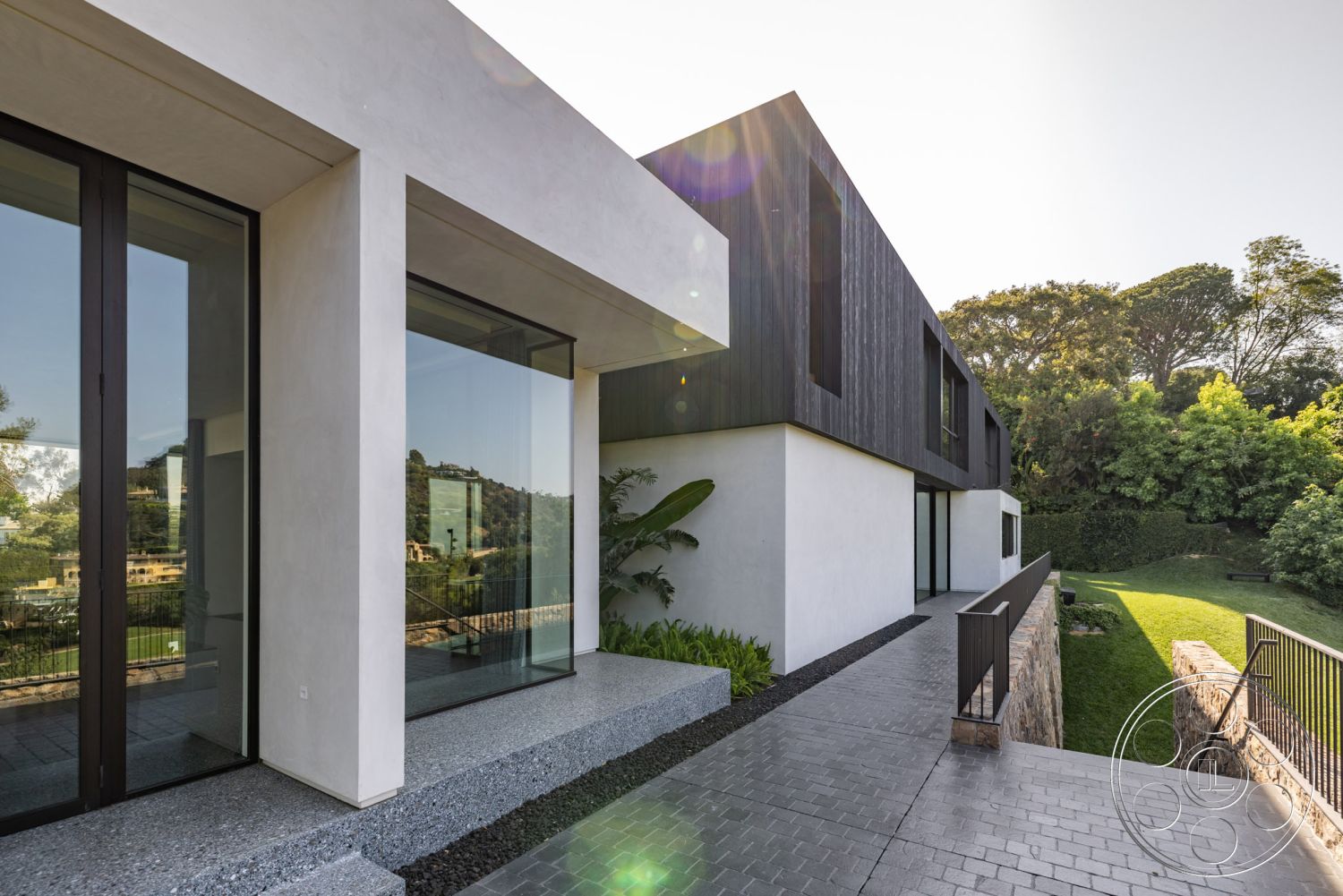 Modern 513 - exterior concrete patio floor, interior open-concept layout, interior floor-to-ceiling windows, exterior white stucco walls, exterior glass sliding doors, interior modern architectural design, interior minimalistic design elements, exterior stone retaining wall, exterior black wood panel siding, exterior landscaped garden with greenery, exterior sleek angular forms, exterior hardscaped pathway, exterior railing with steel balusters, exterior scenic hillside view, exterior subtle texture on wall finishes, exterior ample natural light