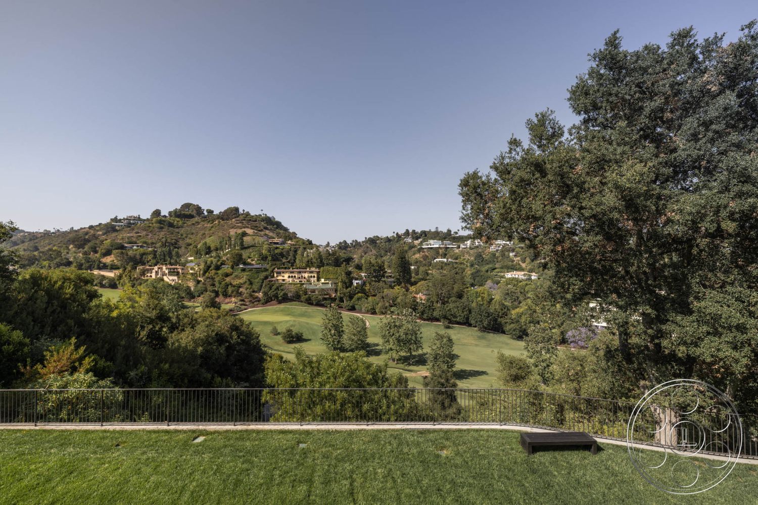 Modern 513 - outdoor living space, hillside location, lush green grass lawn, exterior landscaping features, urban view of neighboring homes, distant mountain backdrop, wood railing terrace, natural vegetation framing, morning sunlight exposure, panoramic view of valley, suburban hillside property, wooden outdoor bench, city skyline silhouette, golf course proximity, tropical trees landscaping