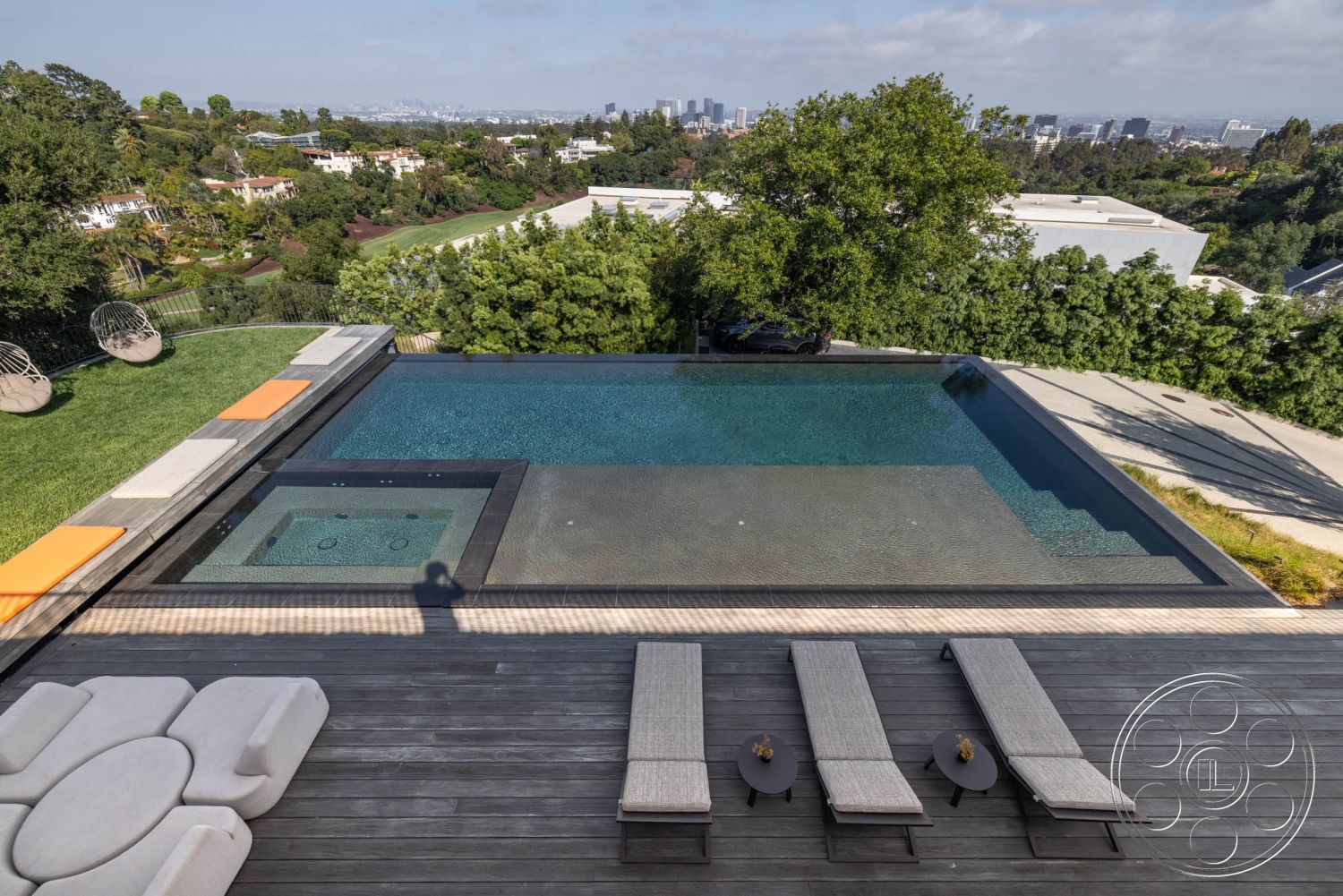 Modern 513 - exterior, surrounding trees, city skyline view, infinity pool, wooden patio furniture, sun deck, concrete pool border, open-air relaxation area, minimalistic outdoor design, modern outdoor lounge chairs, tile surround spa, composite decking patio, landscape with grass lawn, contemporary hillside property, elevated pool area, slate stone drainage