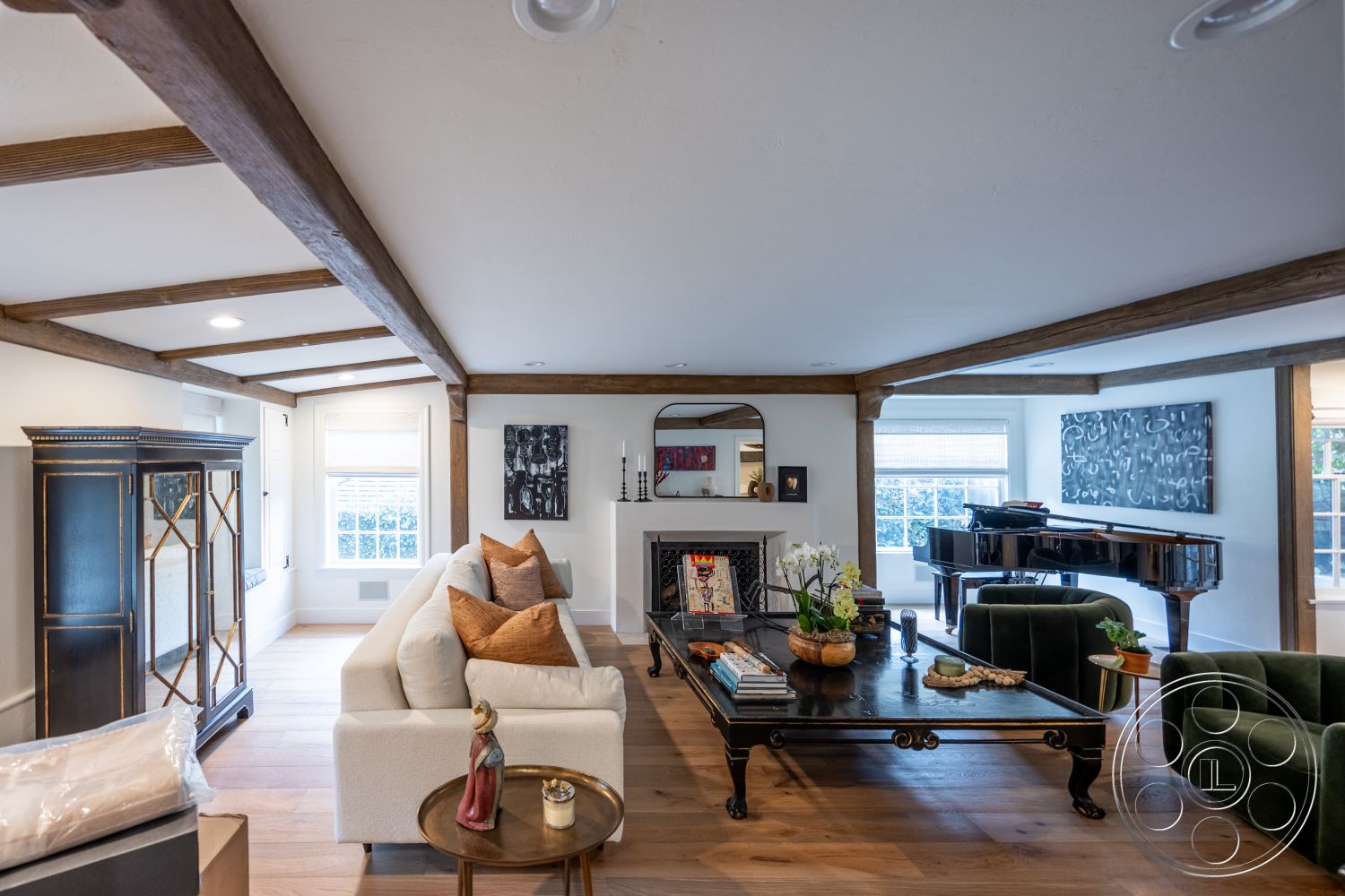 Americana 201 - contemporary decor, interior space, modern aesthetic, floor-to-ceiling windows, dark wood furniture, black grand piano, comfortable seating area, green velvet chairs, rectangular coffee table, exposed wood ceiling beams, natural light setting, hardwood living room floors, textured fabric sofa, white painted walls, stone fireplace surround, glass accent cabinet, detailed wall art