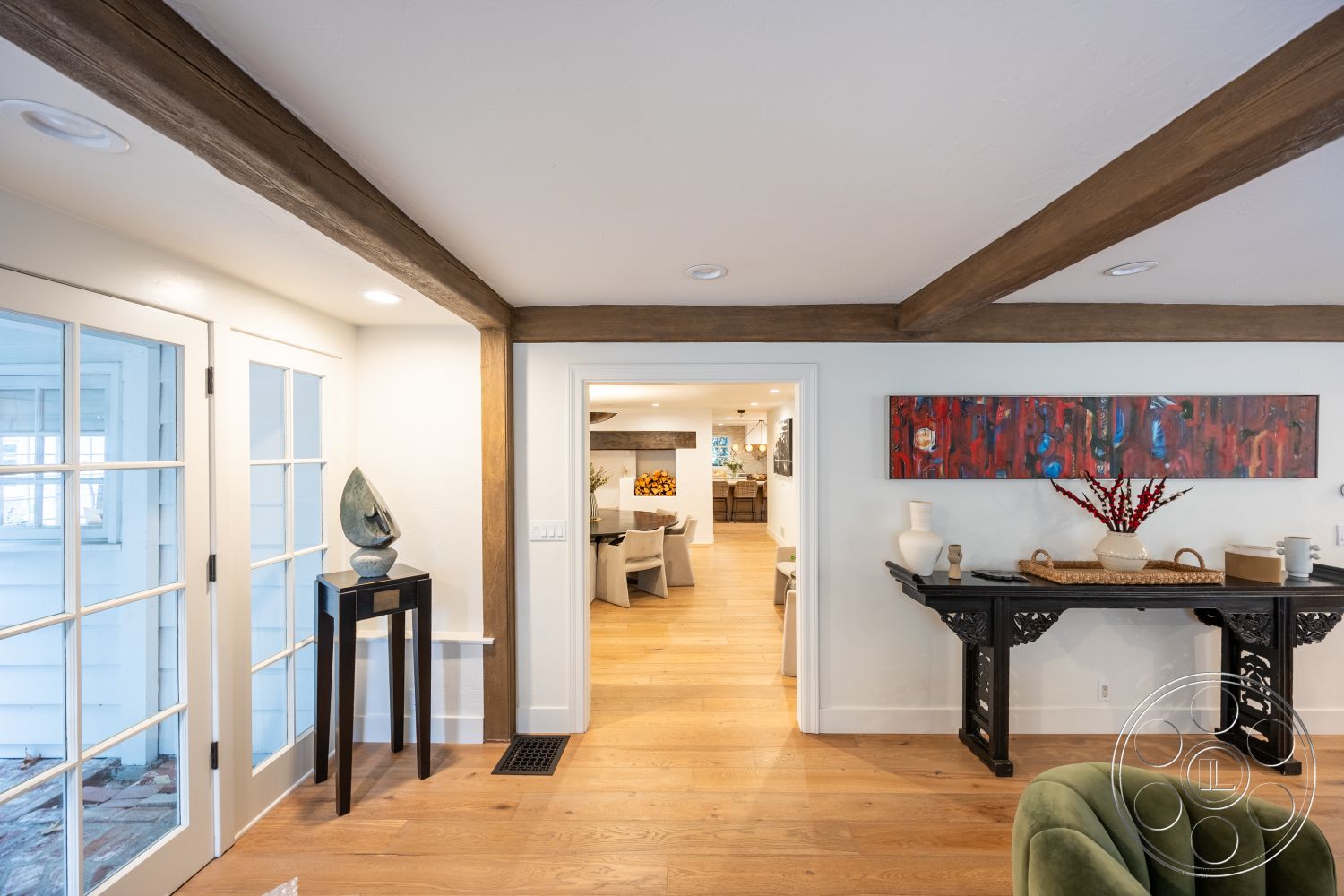 Americana 201 - white painted walls - interior, natural light - interior, exposed wood ceiling beams - interior, open concept layout - interior, oak hardwood flooring - interior entryway, glass panel French doors - interior, dark wooden console table - interior, artistic wall decor - interior, neutral living room area - interior, decorative vase on console - interior