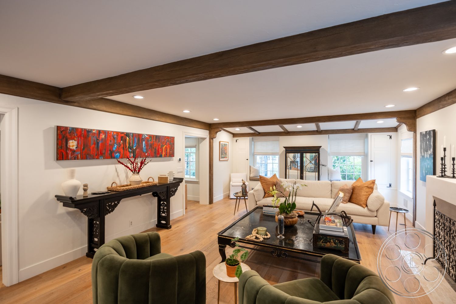 Americana 201 - abstract wall art, modern coffee table, open concept living space, cozy reading nook, exposed wood ceiling beams, hardwood living room floors, white painted walls, natural light filled interior, traditional fireplace surround, green velvet armchairs, console table with decorative accents, twin-paned windows, plush sofa with throw pillows, stylish decorative accessories