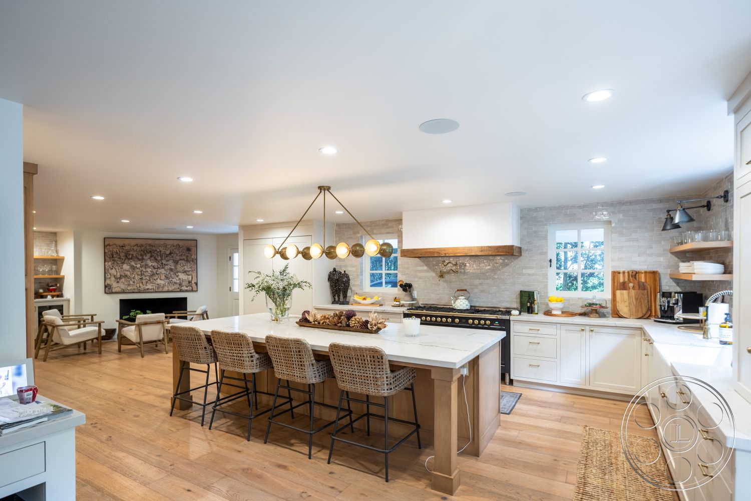 Americana 201 - neutral color palette, textured area rug, open floor plan, woven bar stools, subway tile backsplash, modern pendant lighting, white shaker cabinets, natural light from windows, marble kitchen island countertop, stainless steel range hood, minimalist kitchen design, contemporary dining space, hardwood kitchen floors, built-in shelving units, exposed wood beam ceiling