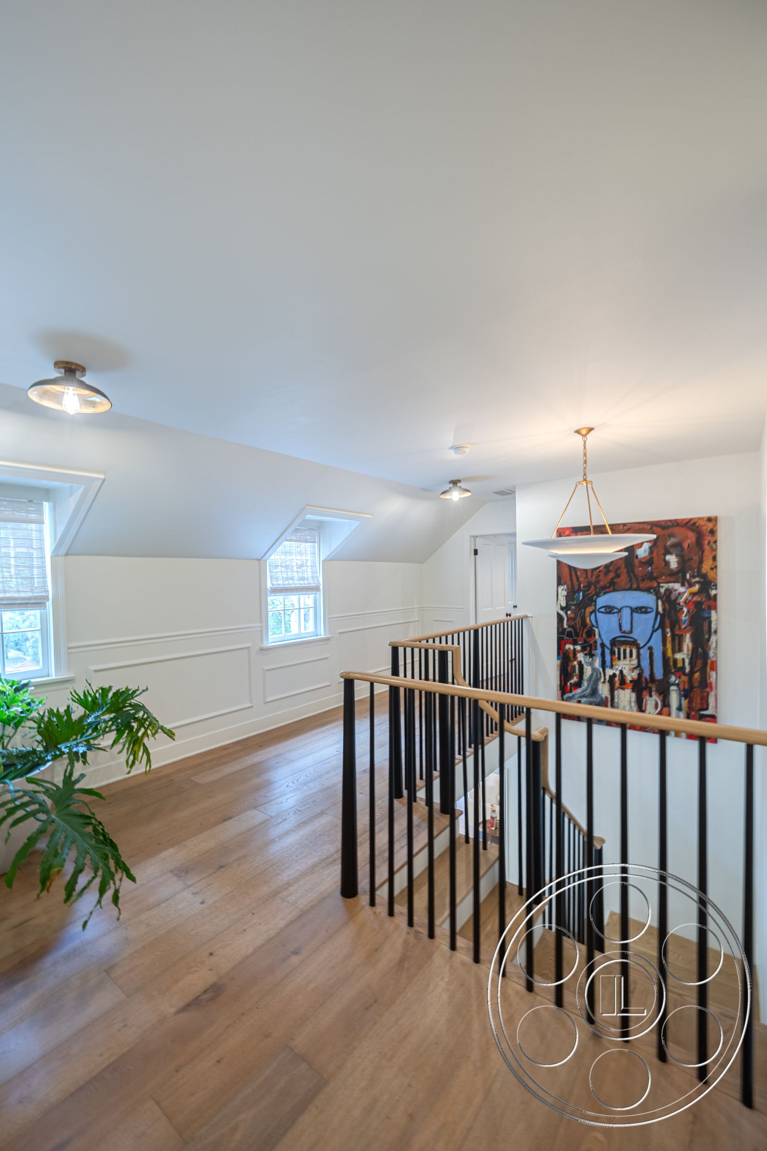 Americana 201 - modern light fixtures, dormer windows, exposed wood ceiling beams, white painted walls interior, interior plant decor, black steel stair railings, coffered ceiling details, artwork wall decor, open staircase design, wainscoting wall treatment, hardwood floor hallway