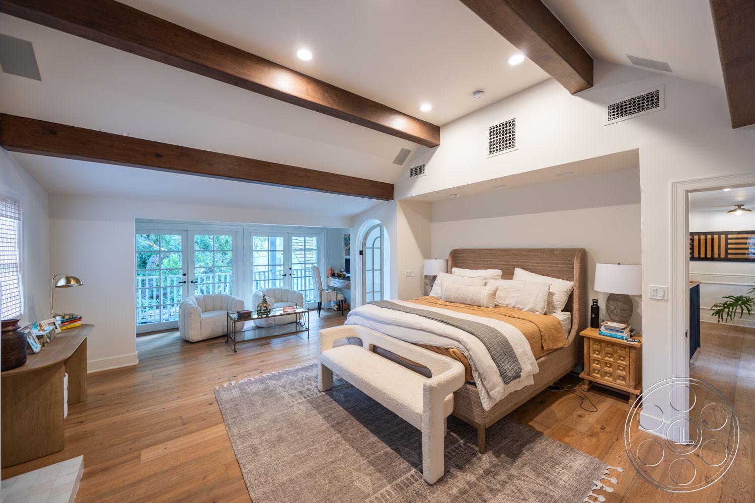 Americana 201 - neutral color palette, natural light, open floor plan, floor-to-ceiling windows, soft area rug, master bedroom, textured plaster walls, exposed wood ceiling beams, hardwood bedroom floors, light-filled interior, white painted walls, king-size bed with upholstered headboard, contemporary bedside tables, urban balcony view