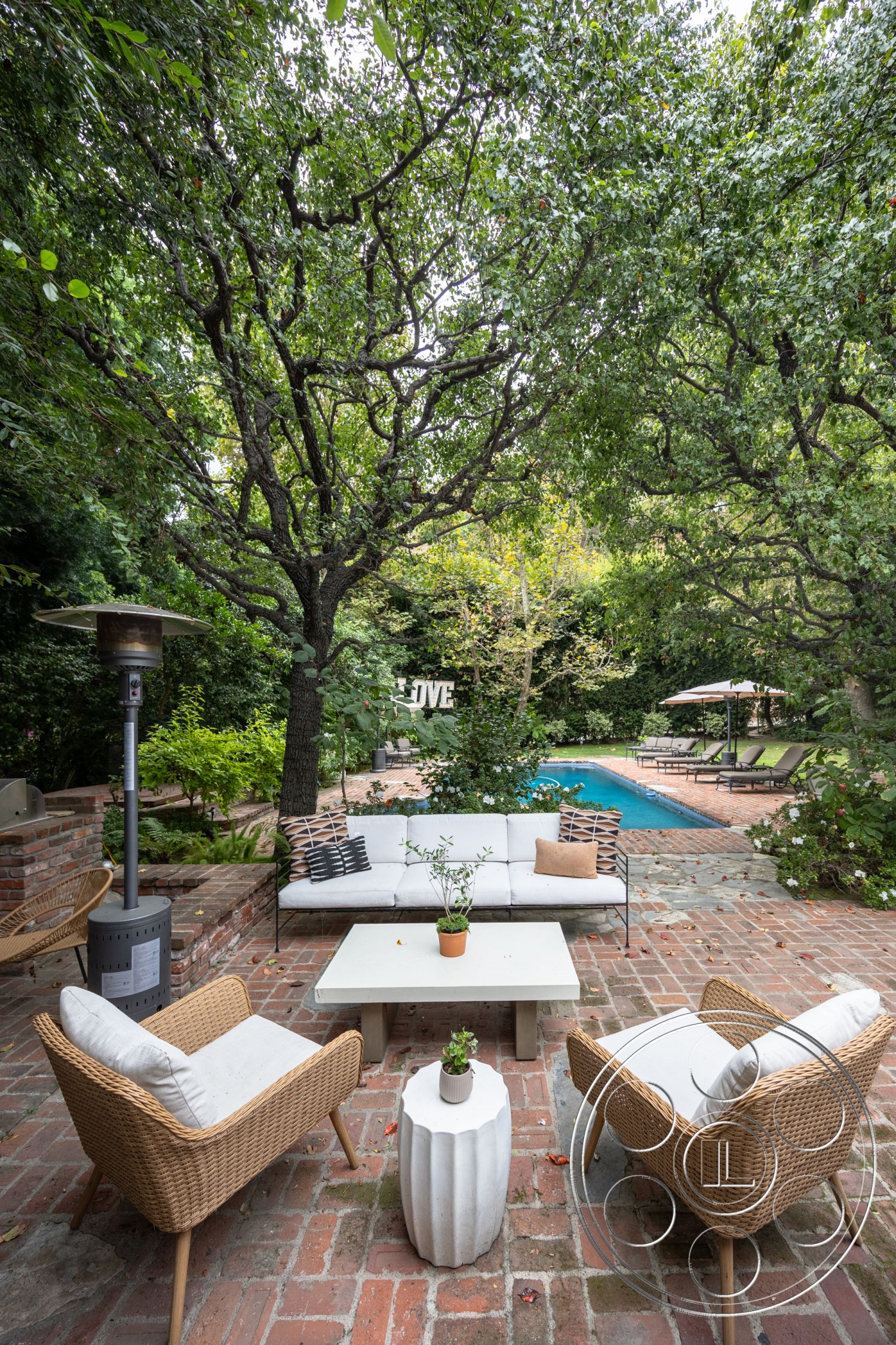 Americana 201 - decorative planter, modern outdoor decor, rectangular pool, poolside lounge area, outdoor heater, concrete coffee table, brick patio flooring, natural stone pool deck, woven outdoor seating, exterior patio space, landscaped garden surroundings, wooden garden planters, lush tree canopies overhead, textured outdoor seating cushions, exposed brick garden wall