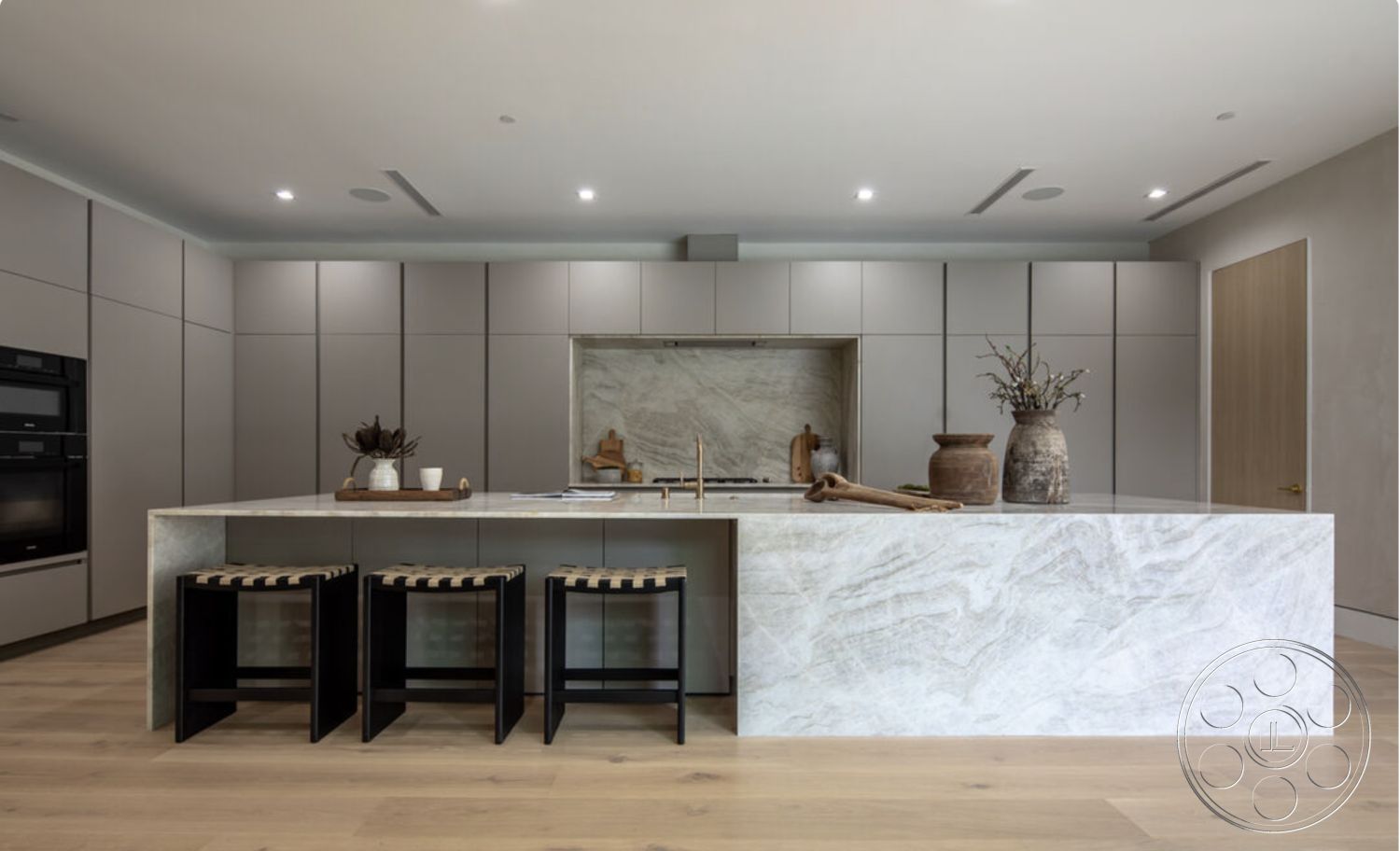 Modern 514 - neutral color palette, light wood flooring, smooth wall finishes, textured stone backsplash, recessed ceiling lights, modern interior design, quartz kitchen countertop, floor-to-ceiling cabinetry, contemporary kitchen layout, matte grey cabinetry, modern open-concept kitchen, minimalist bar stool design, elegant decorative vase, natural light in kitchen, sleek stainless steel appliances