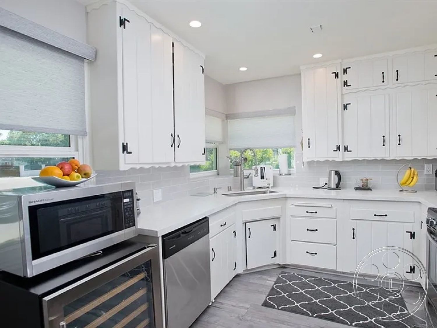 Americana 430 - quartz countertop, neutral color palette, modern pendant lighting, bright interior, laminate flooring, food preparation area, functional kitchen layout, open concept kitchen, stainless steel dishwasher, white subway tile backsplash, minimalist interior, integrated wine cooler, cozy kitchen atmosphere, white shaker kitchen cabinets, stainless steel microwave, curved kitchen countertop, kitchen with plenty of natural light, decorative black cabinet hardware, corner sink placement