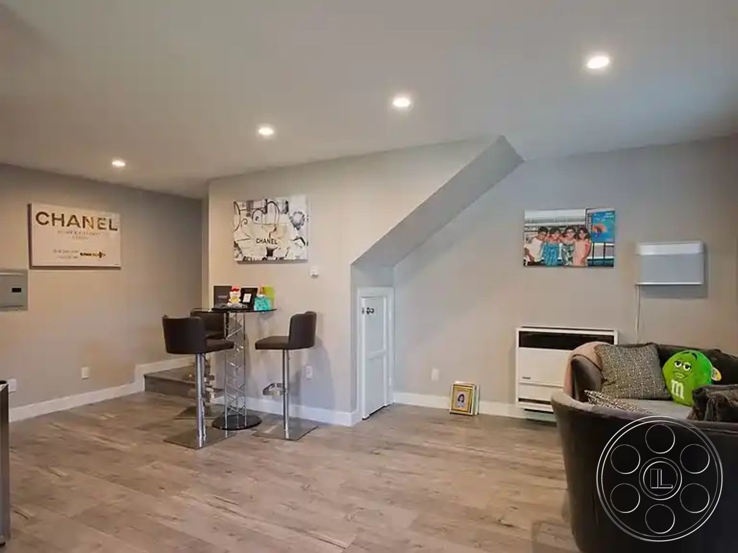 Americana 430 - contemporary furniture, cozy seating area, compact living space, exposed ceiling, bright and airy atmosphere, geometric wall decor, laminate wood flooring, neutral wall paint, recessed LED lighting, modern accent art, minimalist bar table, transparent acrylic bar stools, curved sofa design, under-stair storage, minimalist home office corner, functional open layout