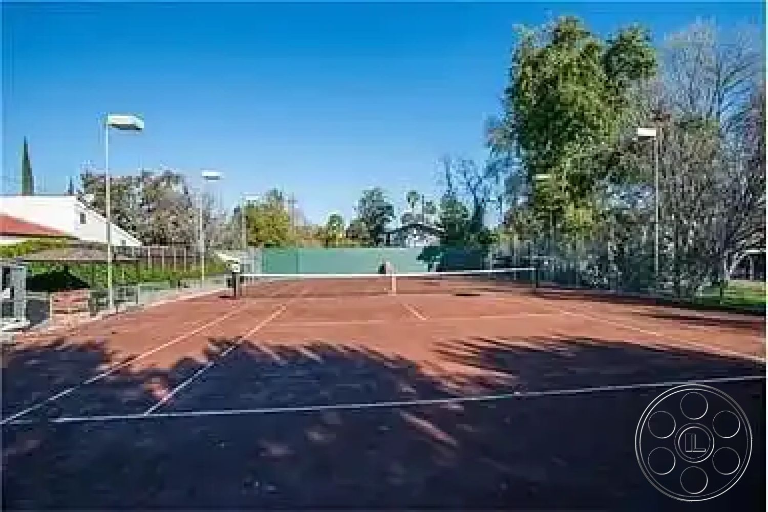 Americana 430 - outdoor recreational space, trees providing shade, residential backyard setting, surrounding landscaped garden, exterior tennis court, red clay court surface, fenced tennis area with lighting, view of neighboring houses