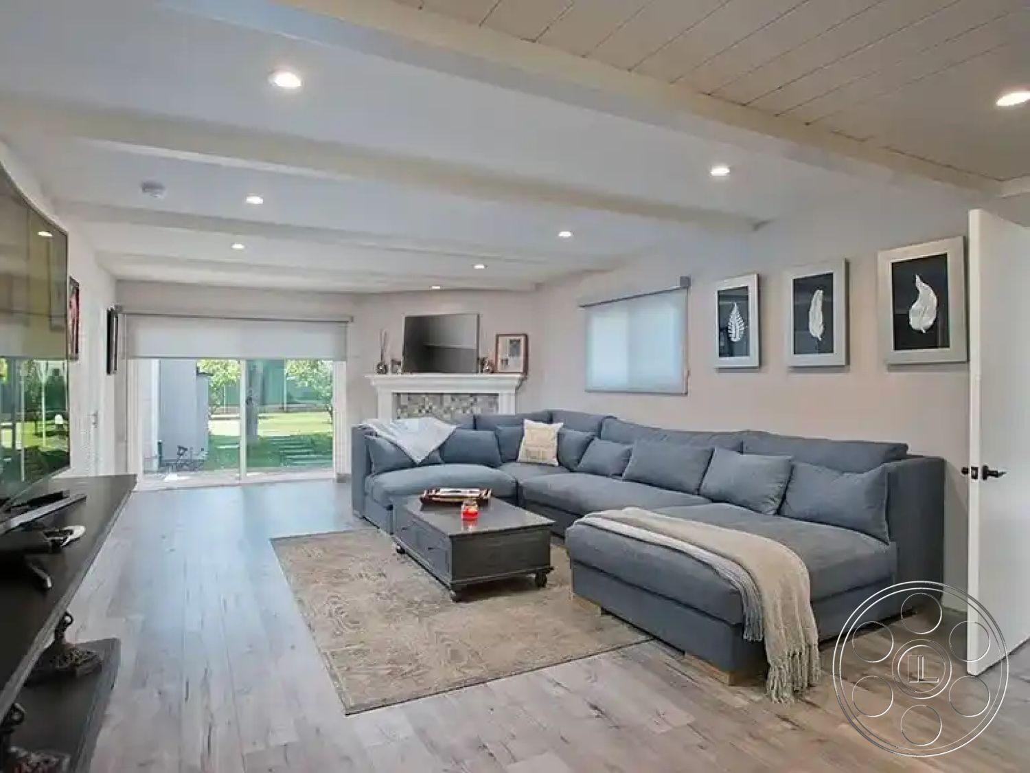 Americana 430 - minimalist decor, neutral color palette, natural lighting, textured area rug, indoor-outdoor flow, floor-to-ceiling windows, sliding glass door, black coffee table, open-concept layout, light gray sectional sofa, exposed wood ceiling beams, interior living space, hardwood living room floors, white painted walls, contemporary ceiling lights, contemporary artwork on walls, modern media console, cozy living room design