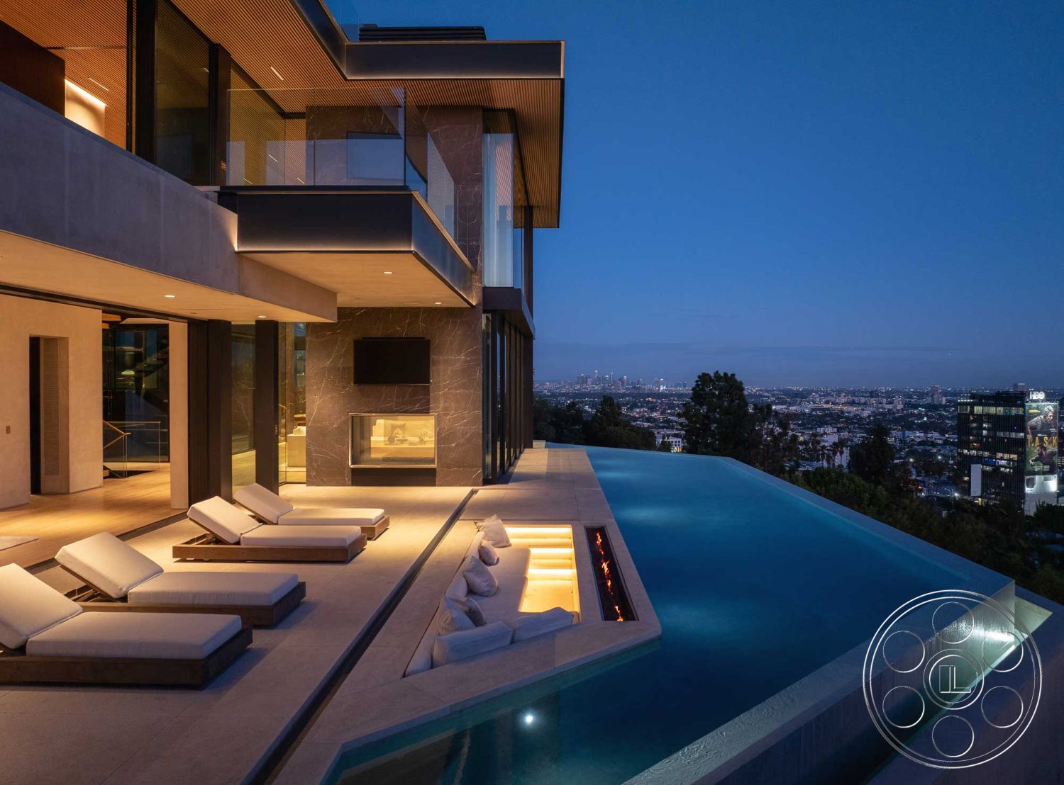 Modern 515 - exterior, wood ceiling, city skyline view, large floor-to-ceiling windows, ambient outdoor lighting, open-concept design, textured stone facade, stone pool deck, contemporary outdoor living space, modern fireplace surround, minimalist architectural style, glass railing balcony, landscaped hillside garden, luxury residential setting, concrete infinity pool, floating lounge chairs, exposed aggregate patio flooring, sleek outdoor entertainment area, sunset illumination, oversized sliding glass doors