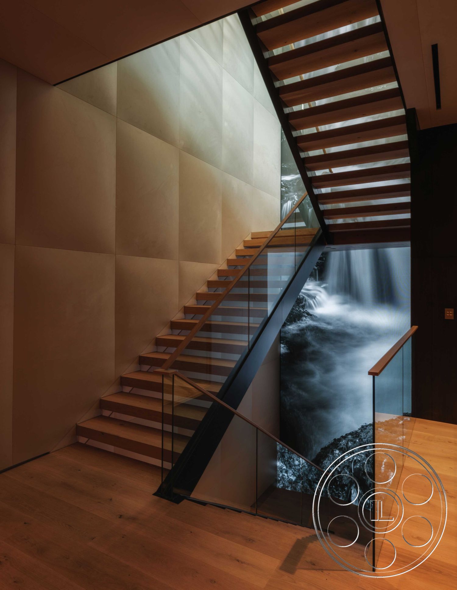 Modern 515 - neutral color palette, natural wood flooring, exposed wood ceiling beams, modern minimalist design, textured plaster wall treatment, floating stairs design, interior staircase with wood treads, glass railings with wood accents, large glass wall with waterfall view, geometric shapes in architectural elements, interior lighting highlighting textures, open-concept space adjacent to stairwell