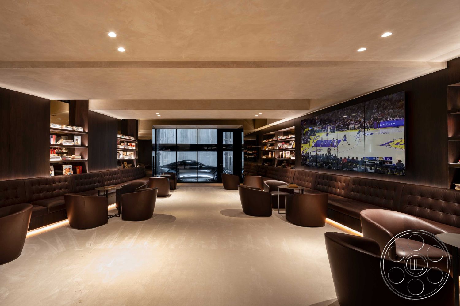 Modern 515 - warm color palette, soft ambient lighting, low-profile seating, dark wood paneling, exposed ceiling structure, built-in bookshelves, hard surface flooring, minimalist design aesthetic, interior lounge space, glass wall partition, smooth plaster wall finish, modern coffee tables, leather upholstered seating, tufted leather banquette, large format wall-mounted display, contemporary lounge layout