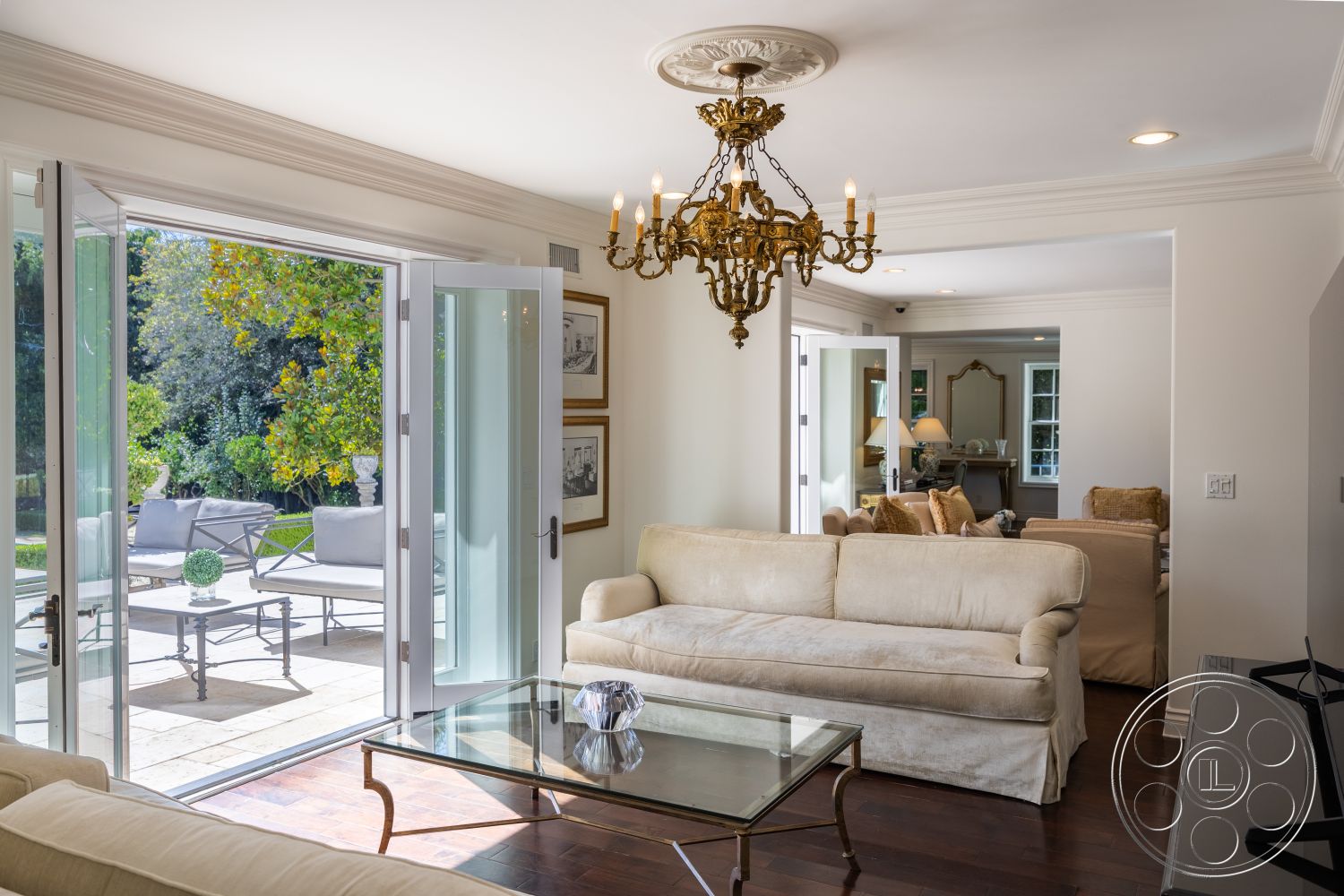 Americana 431 - neutral color palette, natural light, hardwood flooring, glass coffee table, seating area, contemporary furnishings, framed wall art, plush sofa, double French doors, decorative chandelier, interior living room, crown molding details, outdoor patio area, exterior garden view, white wall treatment, elegant home decor
