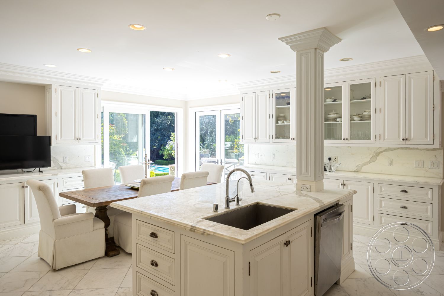 Americana 431 - high ceilings, neutral color palette, stainless steel kitchen appliances, marble kitchen countertops, crown molding details, modern chandelier lighting, marble tile flooring, smooth plaster walls, built-in cabinetry for storage, open-plan kitchen layout, handcrafted wooden dining table, white shaker kitchen cabinets, breakfast bar seating area, glass sliding doors opening to pool area, expansive windows for natural light, interior home office nook, exposed column structure, outdoor dining visibility, backyard garden view, luxury suburban kitchen