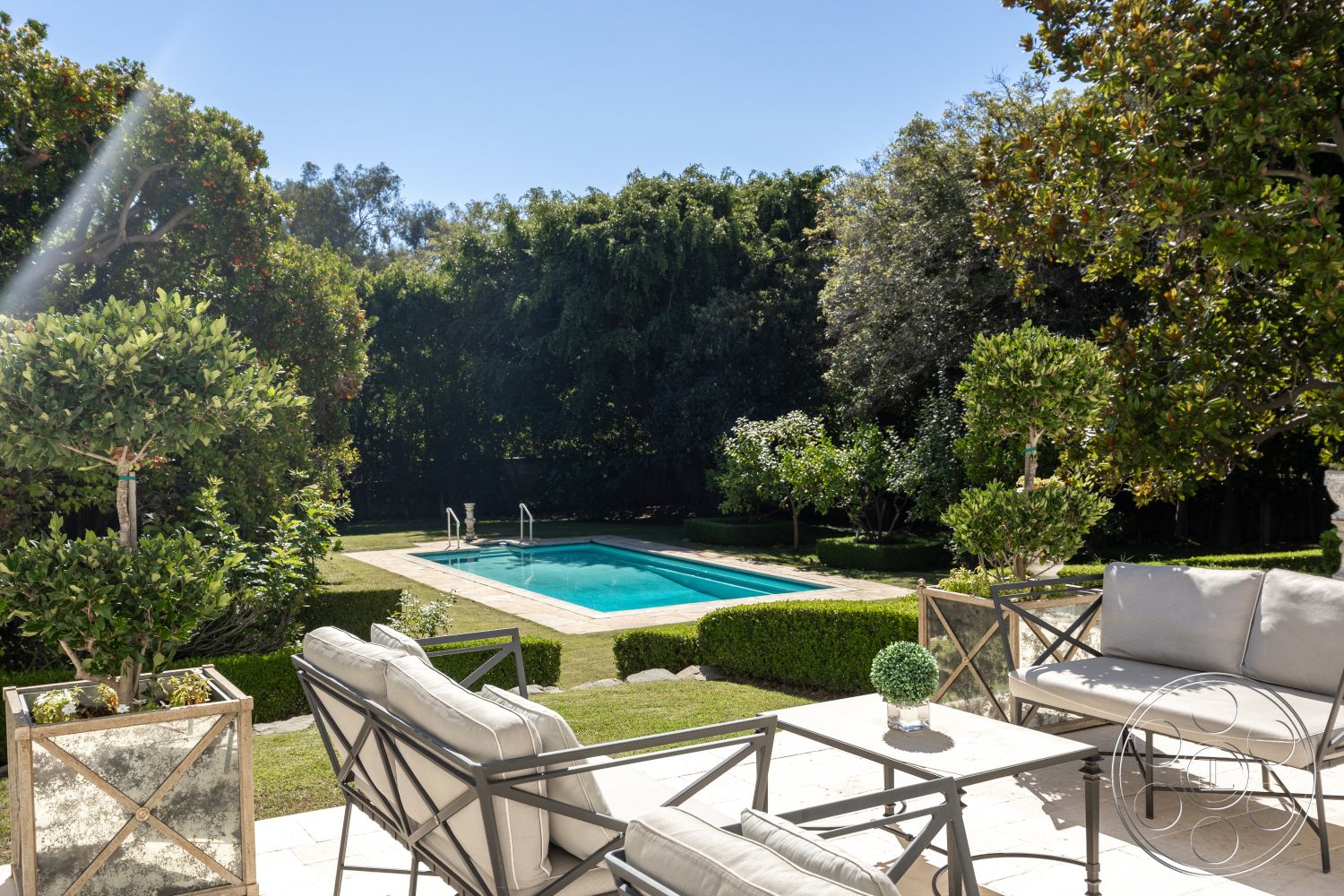 Americana 431 - outdoor seating area, modern outdoor furniture, rectangular swimming pool, decorative planters, sunny outdoor setting, exterior concrete patio floor, private backyard oasis, shrubbery border, tropical garden atmosphere, green landscaped garden, low-maintenance hedges, rectangular pool deck tiles, poolside terrace view