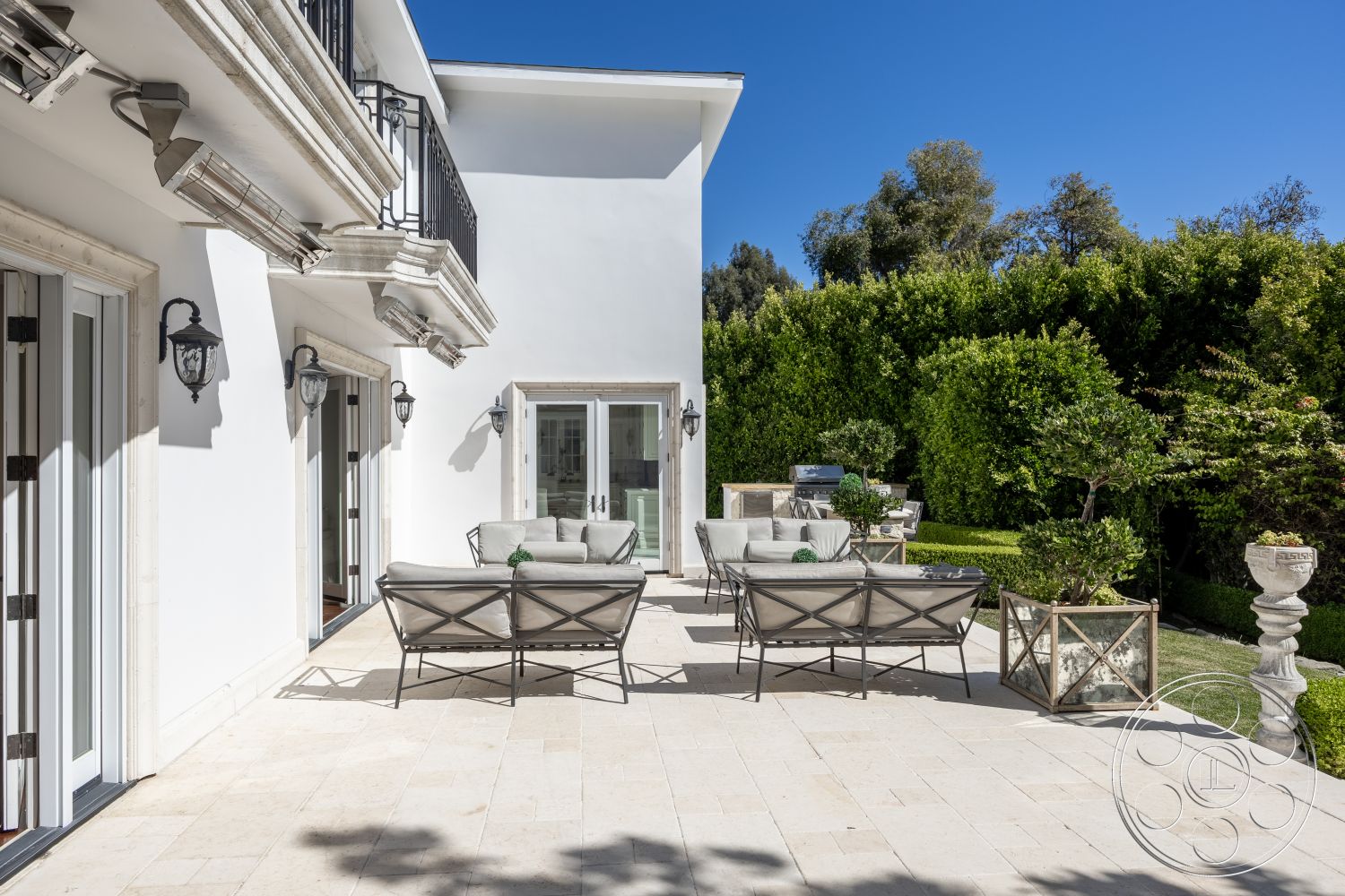 Americana 431 - exterior, outdoor seating area, modern outdoor furniture, large glass doors, elegant light fixtures, greenery backdrop, balcony with wrought iron railings, white painted exterior walls, stone patio flooring, clean lines architecture, landscaped garden with hedges, sunny urban setting, structured garden elements, luxurious exterior design, minimalist patio layout