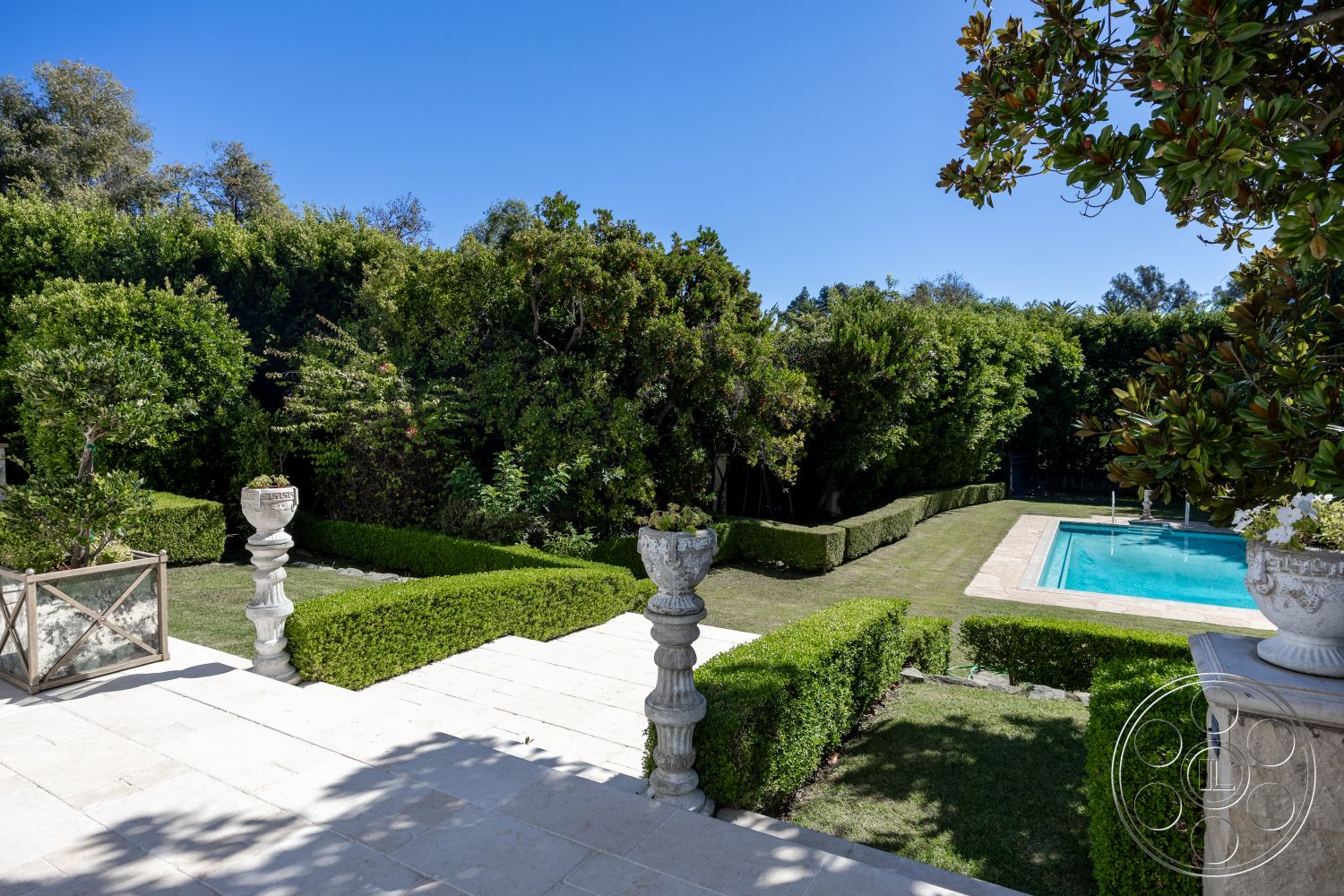 Americana 431 - rectangular swimming pool, landscaped backyard, sunny outdoor area, concrete pool deck, formal garden design, outdoor relaxation space, natural stone steps, exterior stone patio flooring, lush greenery surrounding the pool, mature hedges garden setting, exterior decorative stone planters, hardscape features with manicured lawns, modern garden landscaping, focal point landscape design