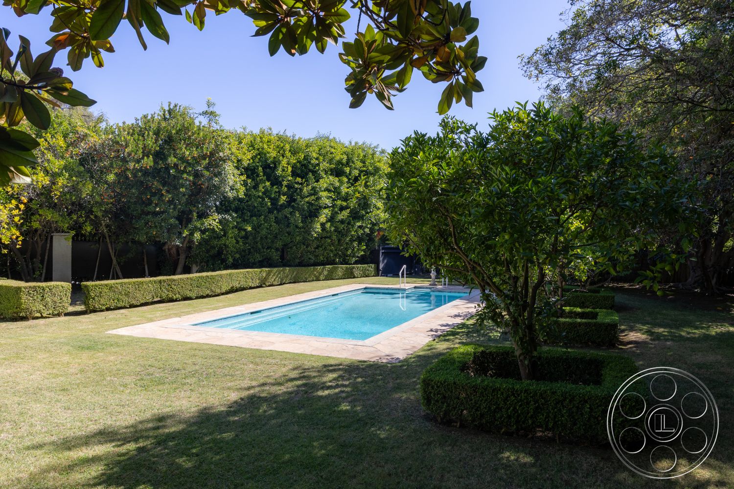 Americana 431 - rectangular swimming pool, green hedges, sunny outdoor space, exterior concrete pool border, landscaped garden setting, private garden oasis, natural stone pool deck, paved patio area, lawns with manicured grass, tropical foliage surroundings, modern poolside area, pool area with lounge potential, clear blue water feature, well-maintained exterior landscaping