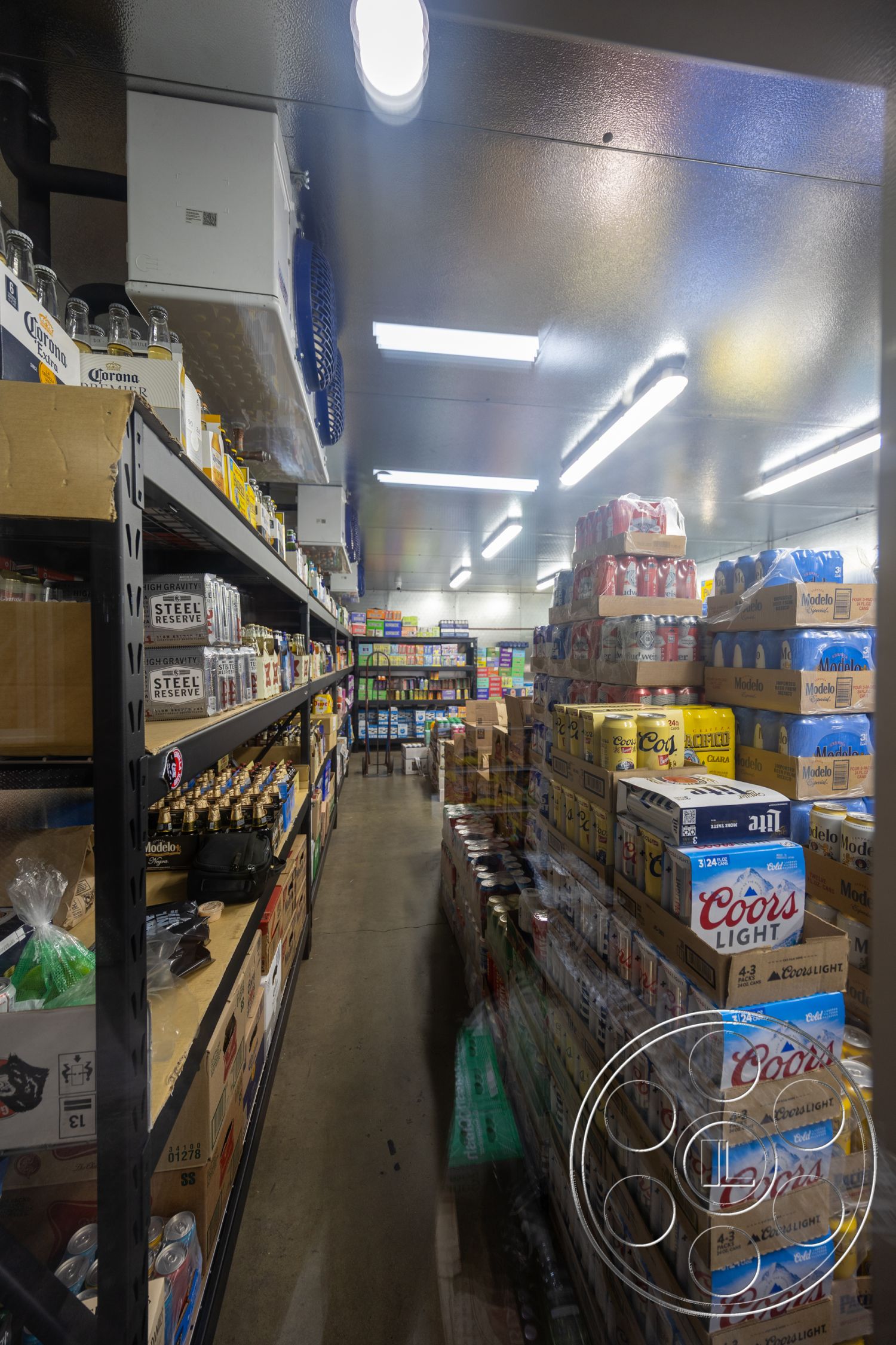 Shop 127 - metal shelving units, ambient ceiling lighting, functional space design, interior storage room, sealed concrete floor, insulated ceiling panels, refrigerated display cases, organized beverage storage, packaged goods aisle, bulk item stacks, warehouse-style interior, minimalist storage layout