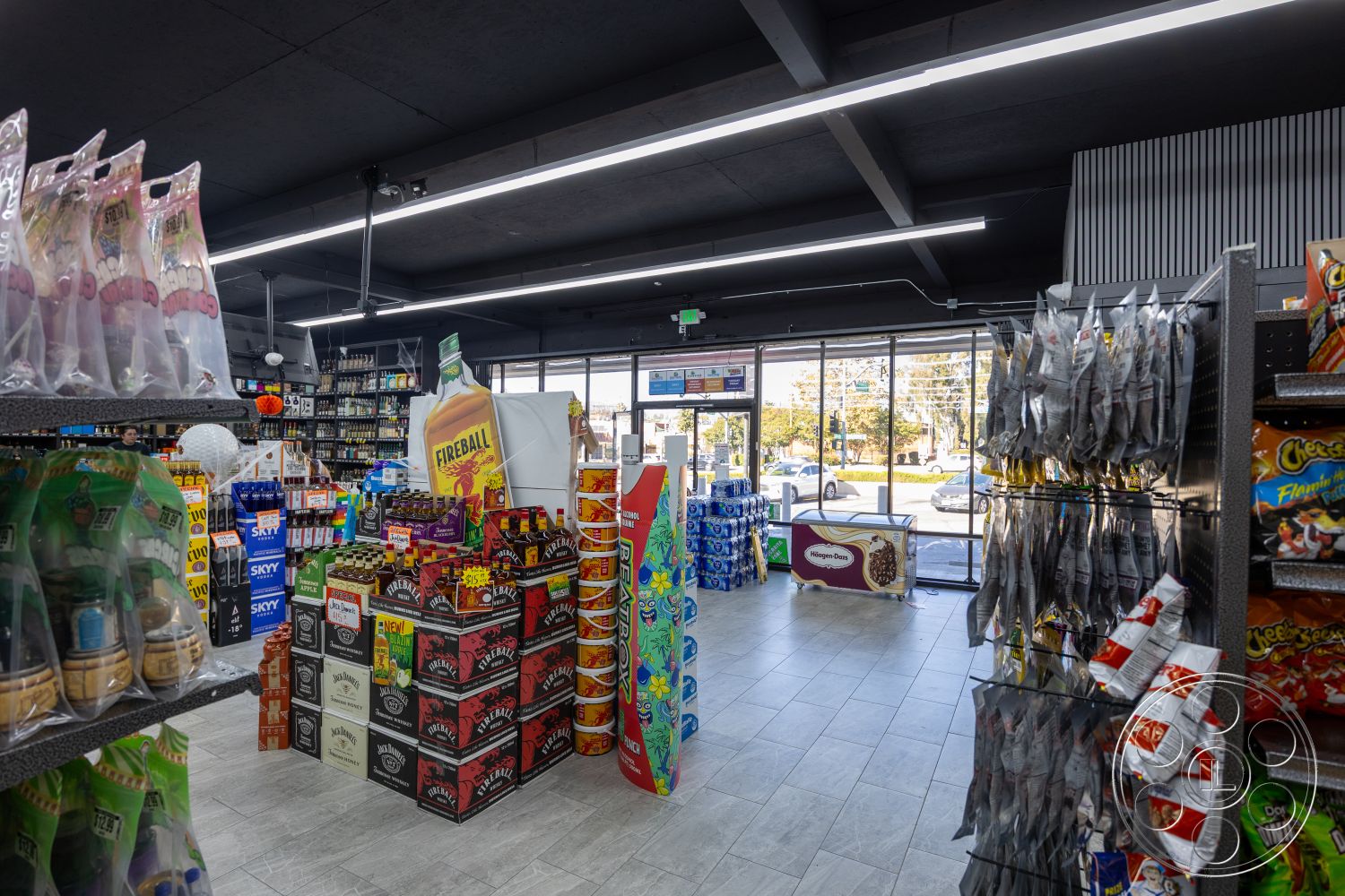 Shop 127 - tile flooring, bright fluorescent lighting, glass storefront windows, modern retail design, interior convenience store, black ceiling panels, open retail space, steel shelving displays, colorful product packaging, varied beverage coolers, product aisle layout, ambient retail environment, organized snack display, clear signage, accessible shopping layout