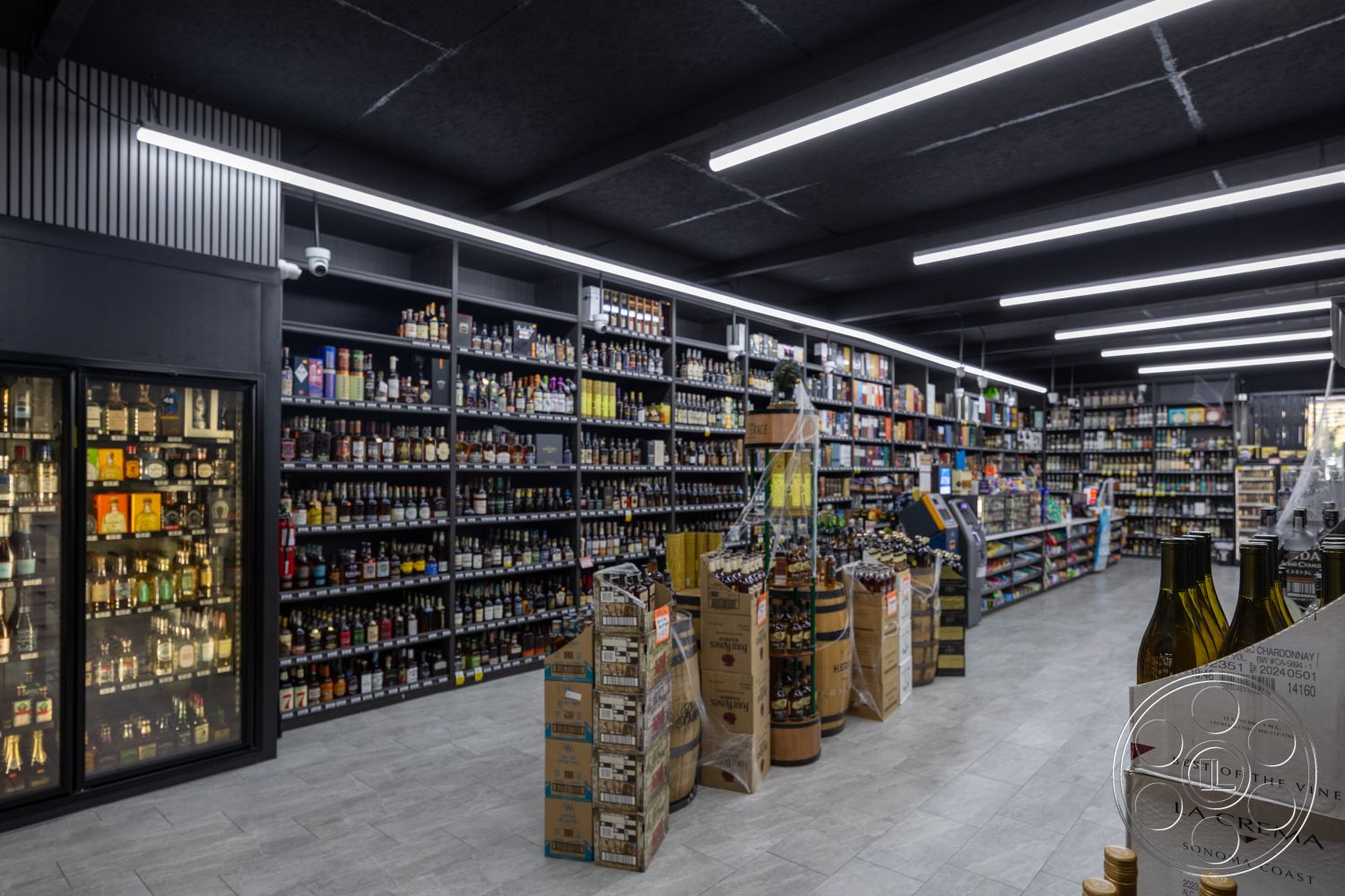 Shop 127 - minimalist aesthetic, open floor plan, polished tile flooring, concrete ceiling, dark wood shelves, industrial style interior, LED strip lighting, modern retail design, interior liquor store, metal display racks, glass refrigerator unit, slatwall paneling, wine display areas, cardboard product displays, ambient store lighting, bottled beverage selection, organized shelving units, commercial space layout, ceiling-mounted security cameras, clear signage for product categories