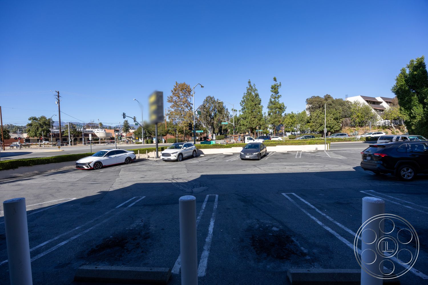 Shop 127 - striped parking spaces, urban commercial setting, exterior parking lot, asphalt parking surface, concrete support columns, tree-lined street view, green hedges surrounding lot, foreground parking spaces, open sky visibility, public transport access close by