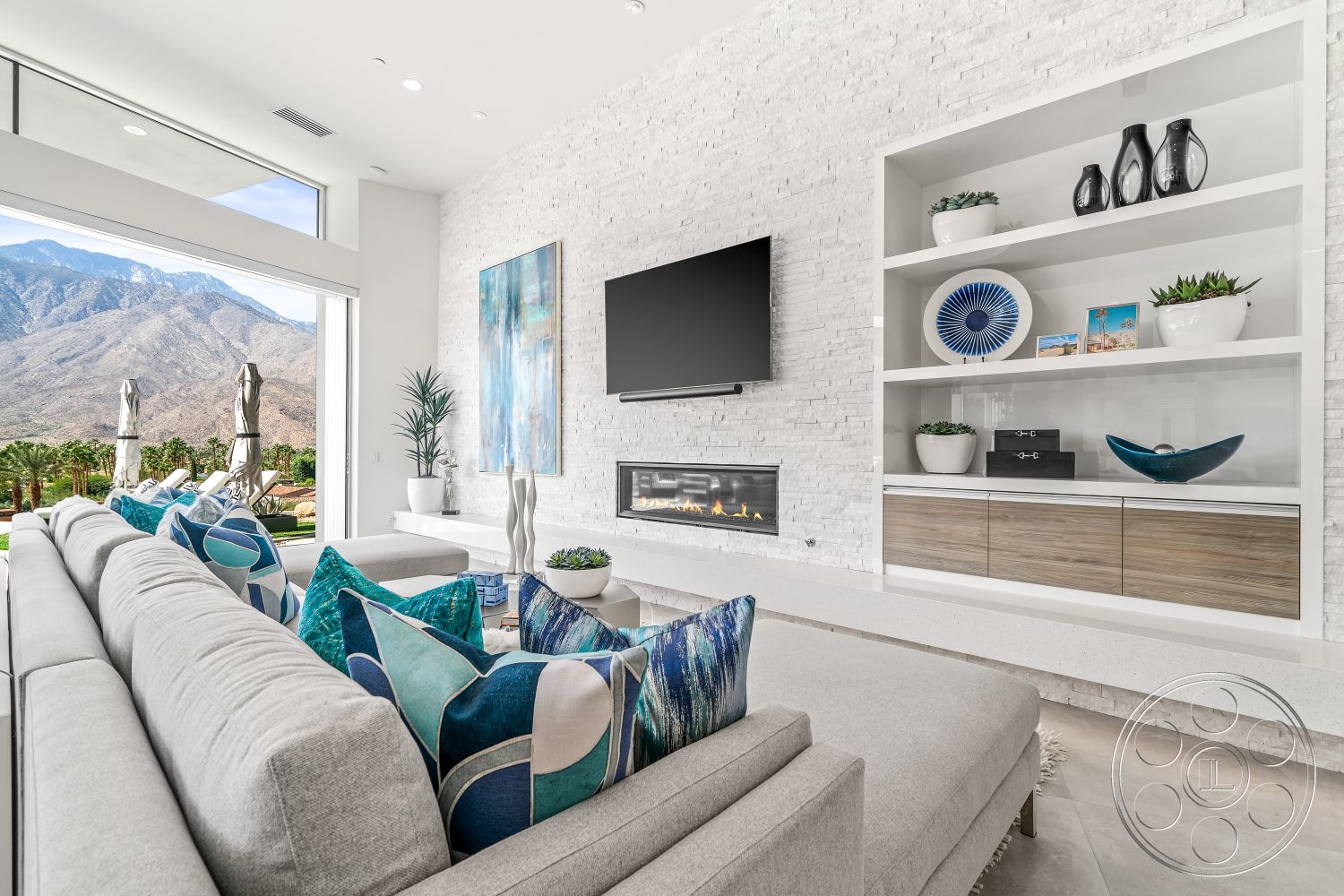 Palm Springs 109 - interior recessed lighting, interior minimalist decor, interior concrete flooring, interior potted greenery, interior open-plan layout, interior glass sliding doors, interior patterned throw pillows, interior light wood cabinetry, interior low-profile sectional sofa, interior built-in shelving unit, interior white brick feature wall, interior linear gas fireplace, interior mounted flat-screen TV, interior mountain view through large windows, interior vibrant abstract art piece