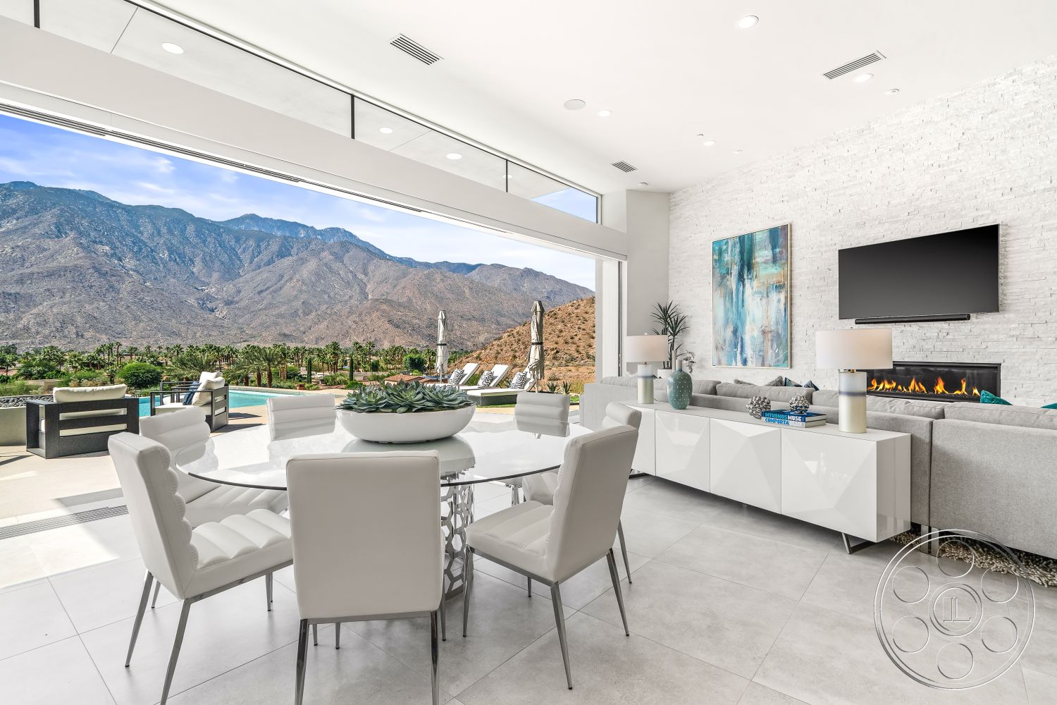 Palm Springs 109 - natural light-filled space interior, open concept living space interior, minimalist coffee table interior, contemporary sectional sofa interior, contemporary lighting fixtures interior, floor-to-ceiling windows with mountain view interior, white painted brick accent wall interior, smooth porcelain tile flooring interior, modern round dining table interior, high-backed upholstered dining chairs interior, view of infinity pool from living area interior, mounted flat-screen television interior, decorative potted plants interior, stylish vases with modern decor interior, textured wall art interior, sliding glass doors leading to outdoor patio interior, luxurious outdoor living space exterior, landscaped backyard with palm trees exterior, mountain landscape view exterior, resort-style outdoor lounge chairs exterior, modern exterior architecture with clean lines, poolside area adjoining the patio exterior, seamless indoor-outdoor flow design exterior