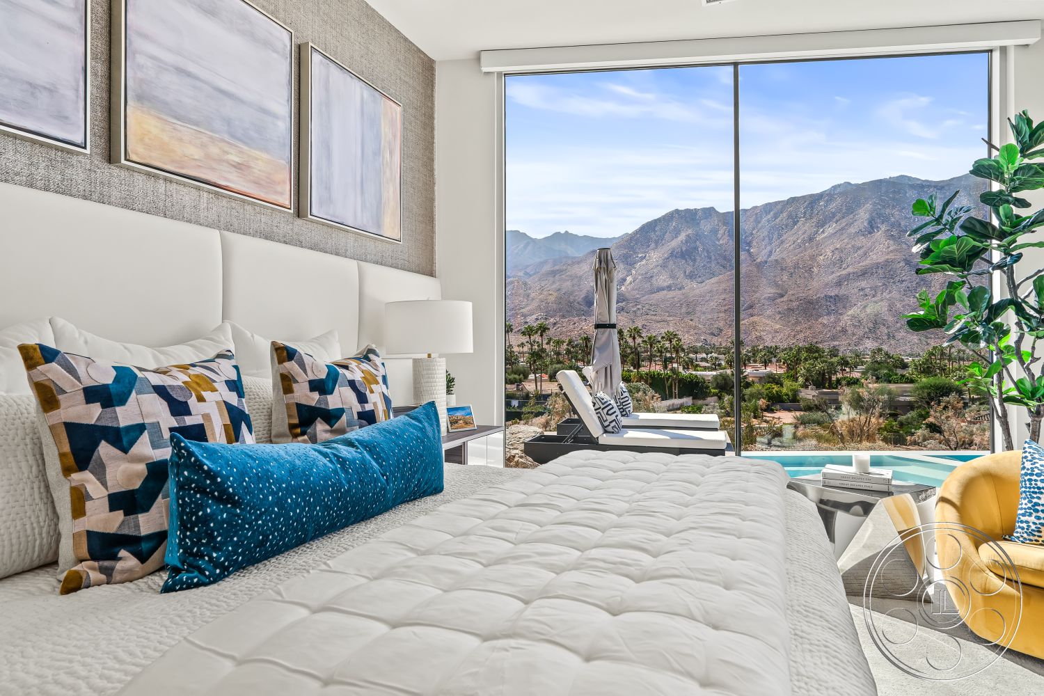 Palm Springs 109 - soft neutral color palette, textured wall treatment, colorful accent pillows, sunlit ambiance, stylish accent chair, modern lounge chairs, natural light-filled space, interior bedroom space, floor-to-ceiling glass windows, mountain view from bedroom, minimalist bedside lamp, white upholstered headboard, luxury bedding with geometric patterns, creamy tufted bedspread, clear glass sliding doors, light-colored decorative side table, contemporary indoor plant decor, cozy corner reading area, open concept bedroom, contemporary art wall hangings