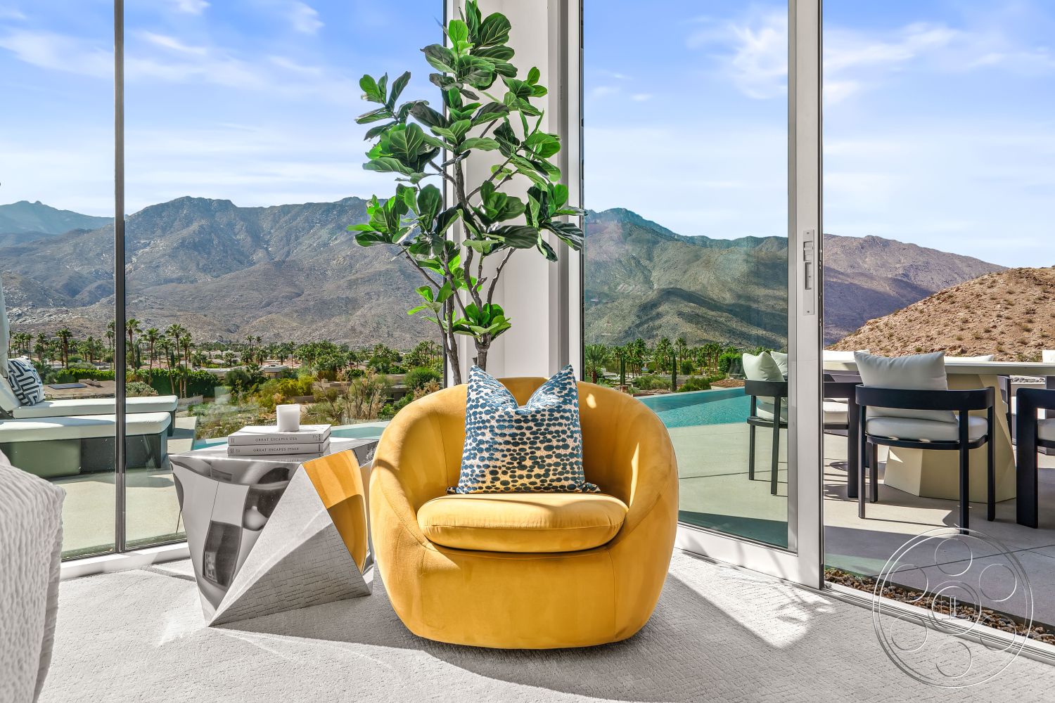 Palm Springs 109 - minimalist design aesthetic interior, floor-to-ceiling glass windows interior, natural light-filled living space interior, yellow velvet accent chair interior, glass wall with mountain view interior, outdoor pool area with desert landscape, concrete patio flooring exterior, modern geometric side table interior, potted indoor plant interior, sunny mountain retreat setting exterior, soft area rug flooring interior, bright accent pillow interior, contemporary outdoor dining area exterior