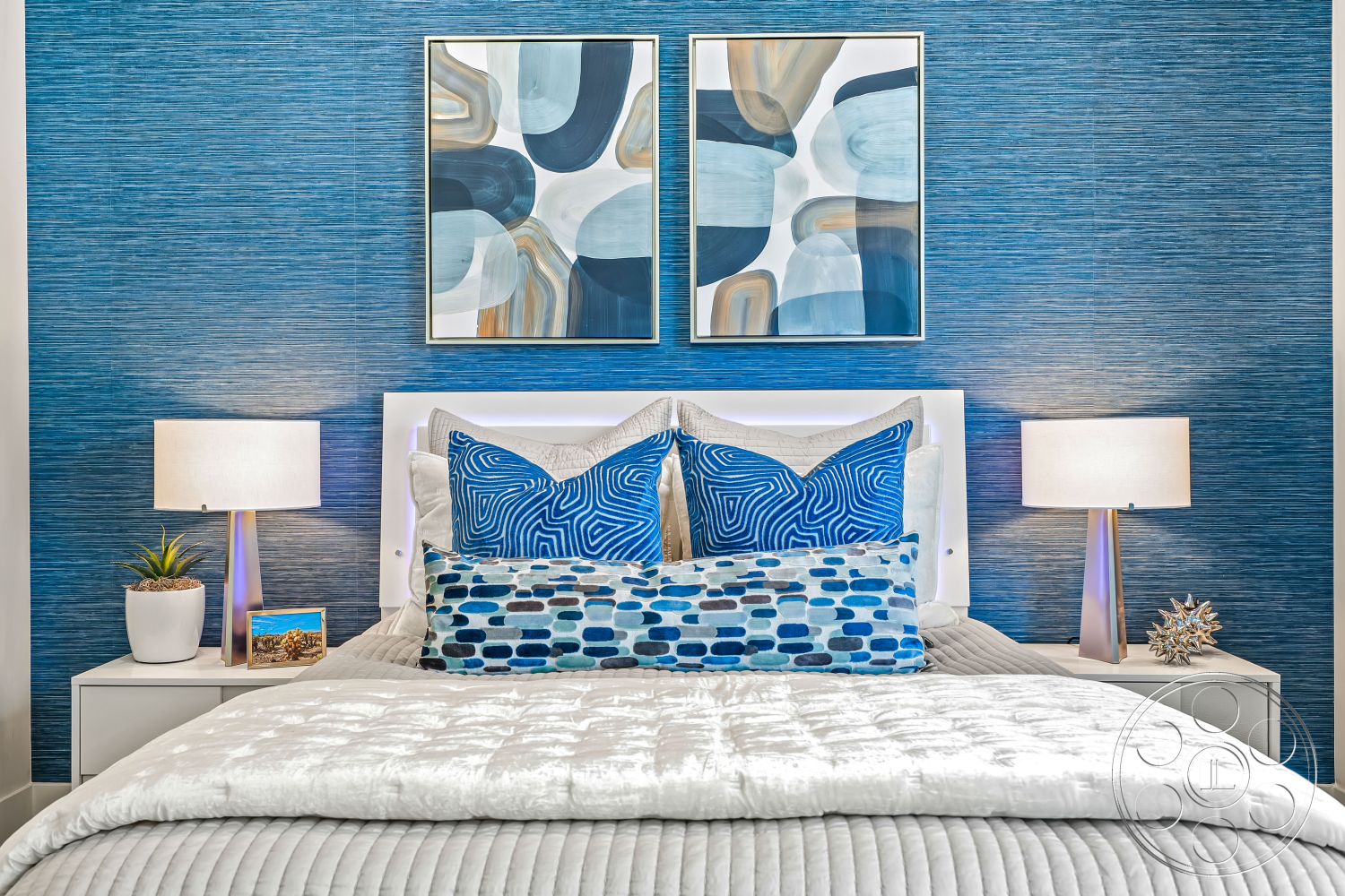 Palm Springs 109 - contemporary design elements, soft ambient lighting, smooth wood flooring, interior bedroom, modern artwork on wall, blue textured wallpaper, king-size bed with white quilted bedding, decorative blue patterned throw pillows, nightstands with minimalist design, table lamps with metallic bases, small indoor plant in white ceramic pot, framed photo on nightstand