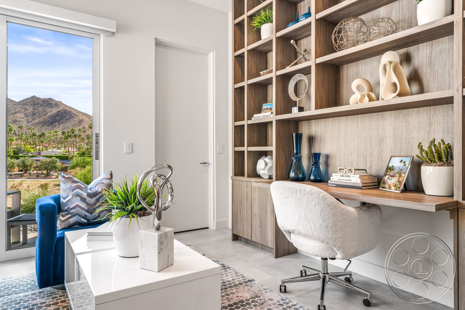 Palm Springs 109 - minimalist decor, neutral color palette, polished concrete floor, concrete flooring, modern lighting fixtures, sliding glass door, natural wood finishes, open layout design, interior home office, geometric decorative elements, wooden built-in bookcase, contemporary desk chair, mountain view through large windows, indoor plants with natural light, textured wall shelving