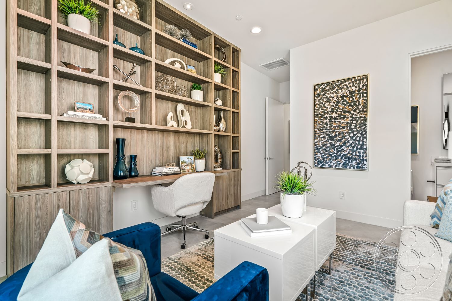 Palm Springs 109 - white textured walls, cozy reading nook, white cabinetry with minimalist design, light-filled space with natural light, open shelving unit with natural wood finish, contemporary desk area with ergonomic chair, neutral colored tile flooring, decorative geometric art piece, green indoor plants as decor, modern abstract decor accents, blue velvet accent chairs, minimalist coffee table with white surface, plush throw pillows with geometric patterns, functionally designed home office